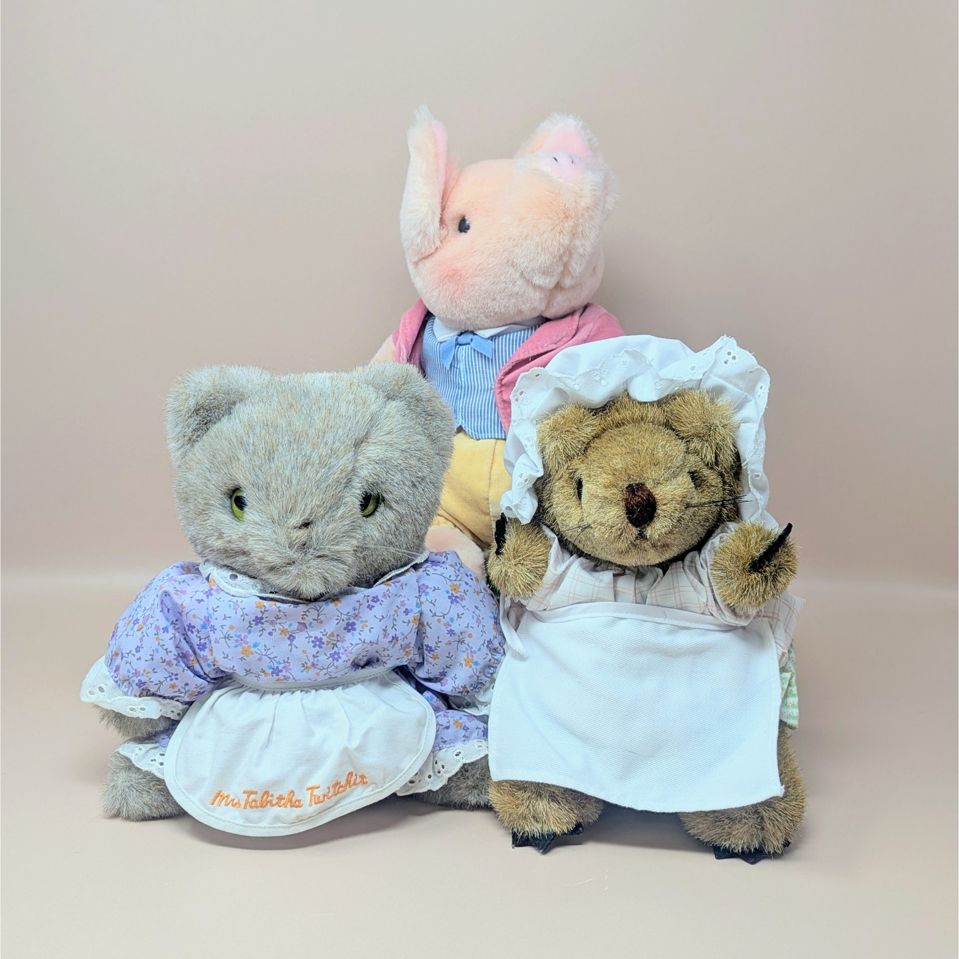 A 3-piece vintage plush set by Eden featuring Beatrix Potter characters: Pigling Bland in a pink jacket, Mrs. Tabitha Twitchit in a floral dress and apron, and Mrs. Tiggy-Winkle in a white cap and apron.