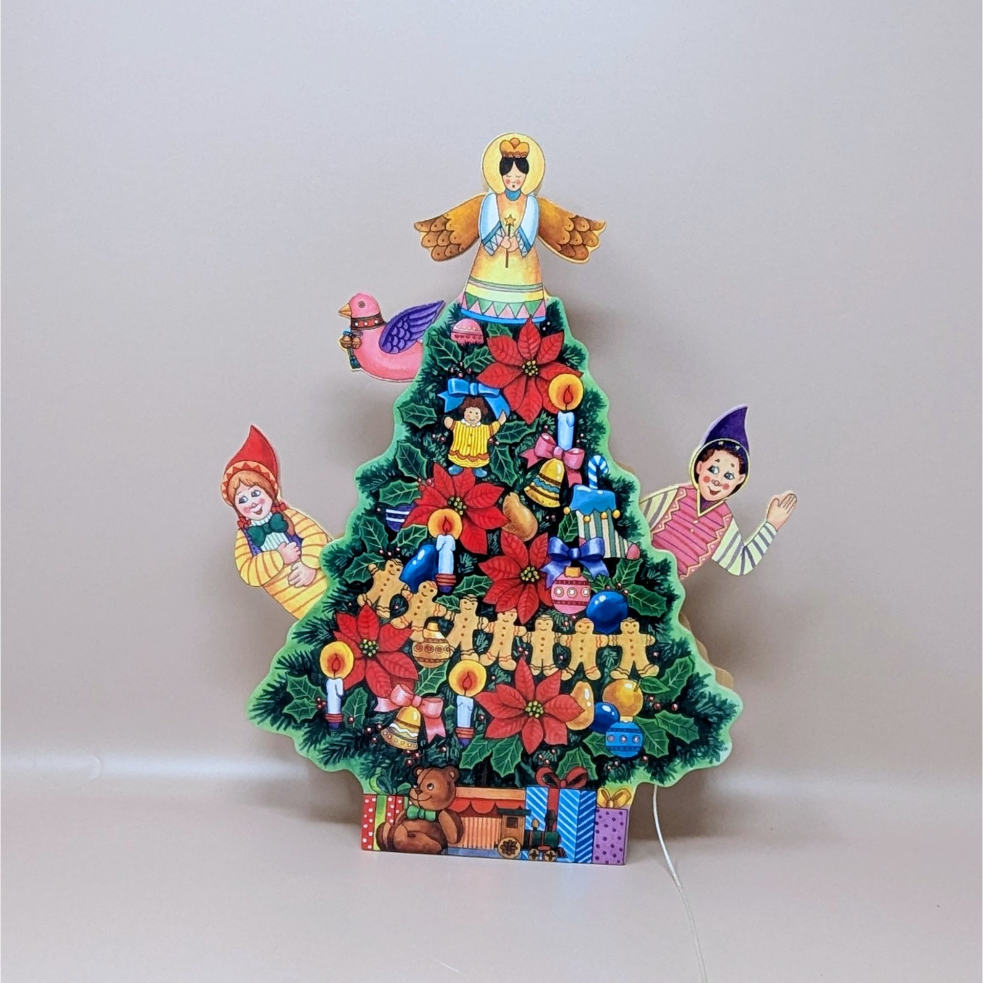 A vintage musical wooden Christmas tree. The flat, layered wood tree features colorful illustrations of an angel topper, poinsettias, elves, and a train set at the base.