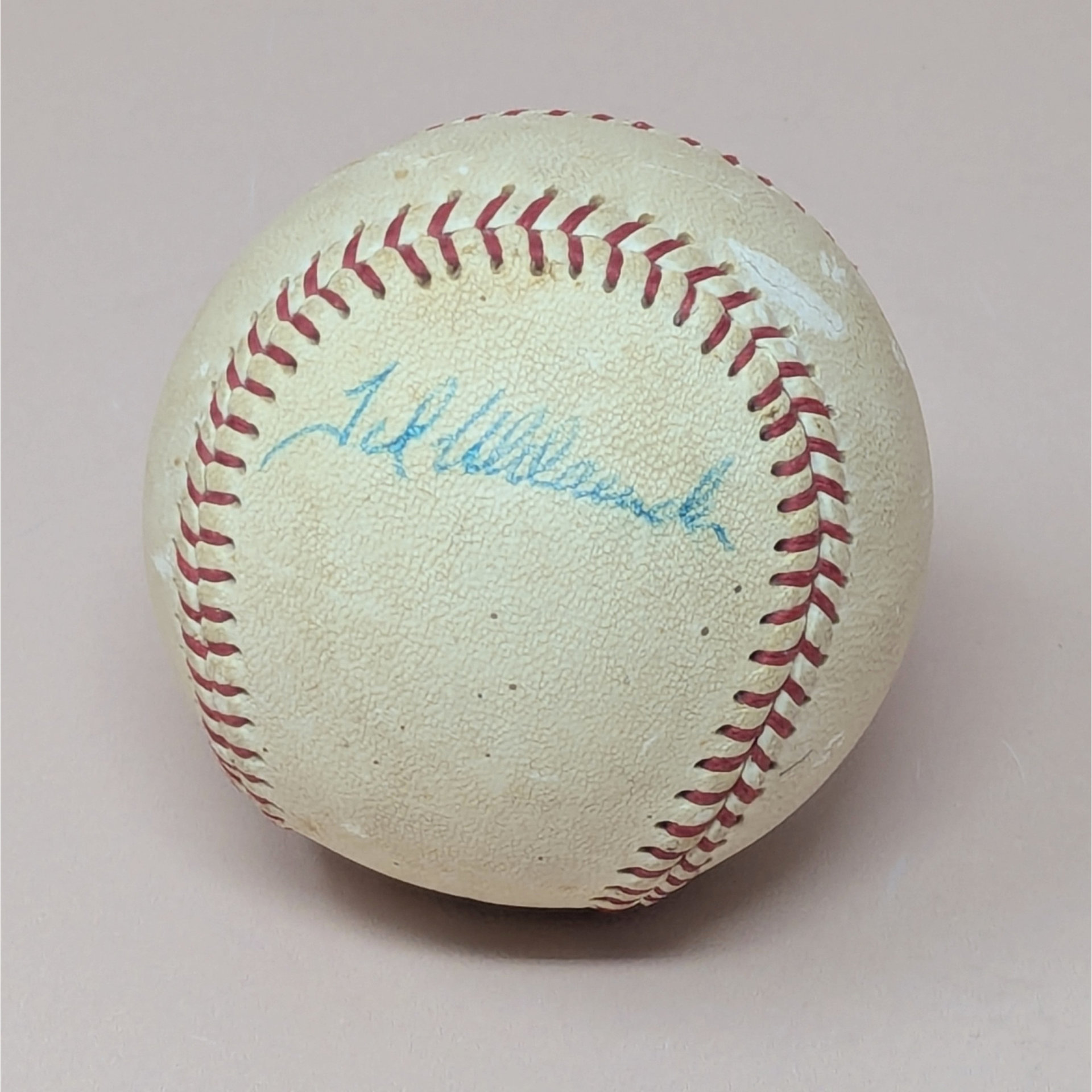 A vintage Wilson Little League baseball featuring a blue ink signature from Minnesota Twins player Ted Uhlaender. The ball shows natural cream-colored toning and some scuffing consistent with age.