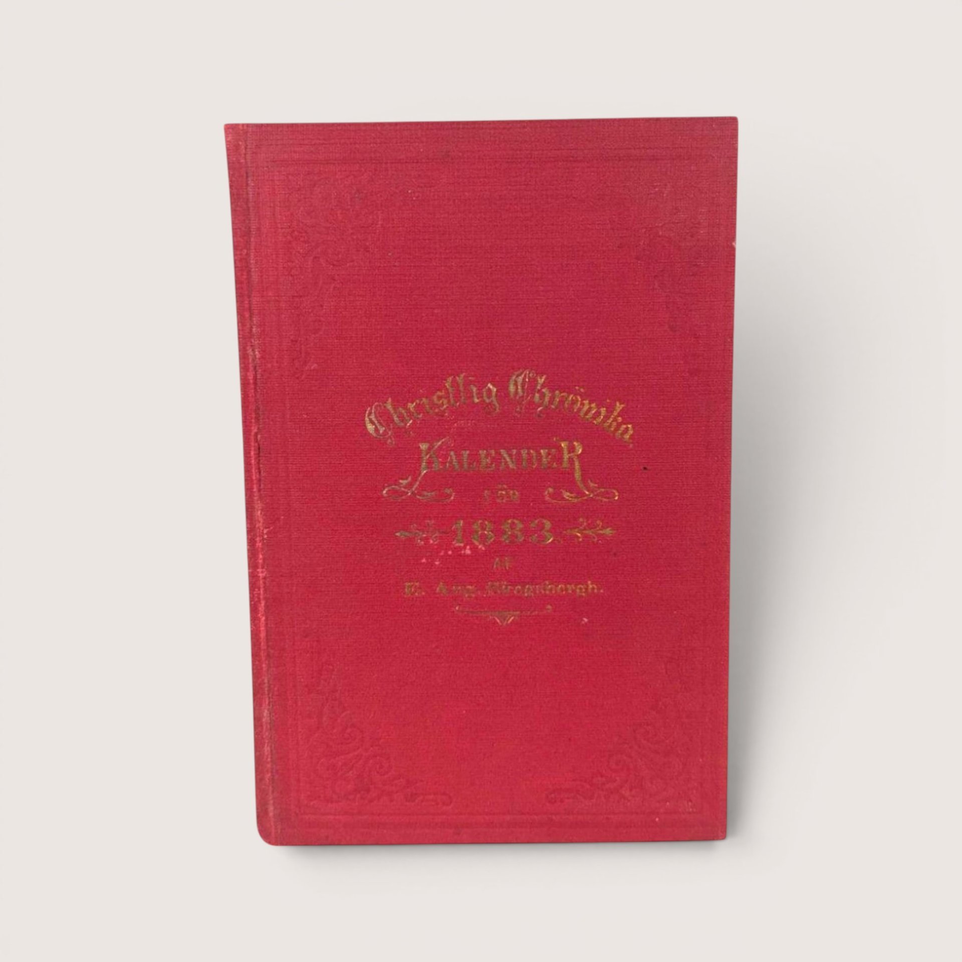 Antique red cloth hardcover book with gold gilt lettering titled Christlig Chronika Kalender for 1883.