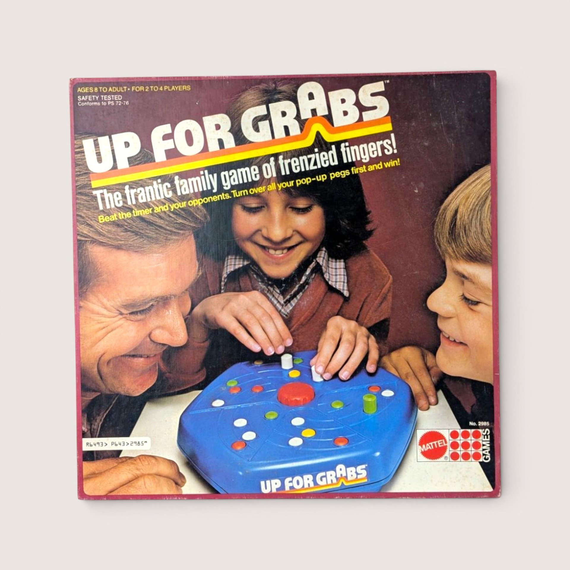 Vintage Up For Grabs board game box cover featuring a photograph of a smiling family playing a mechanical blue game.