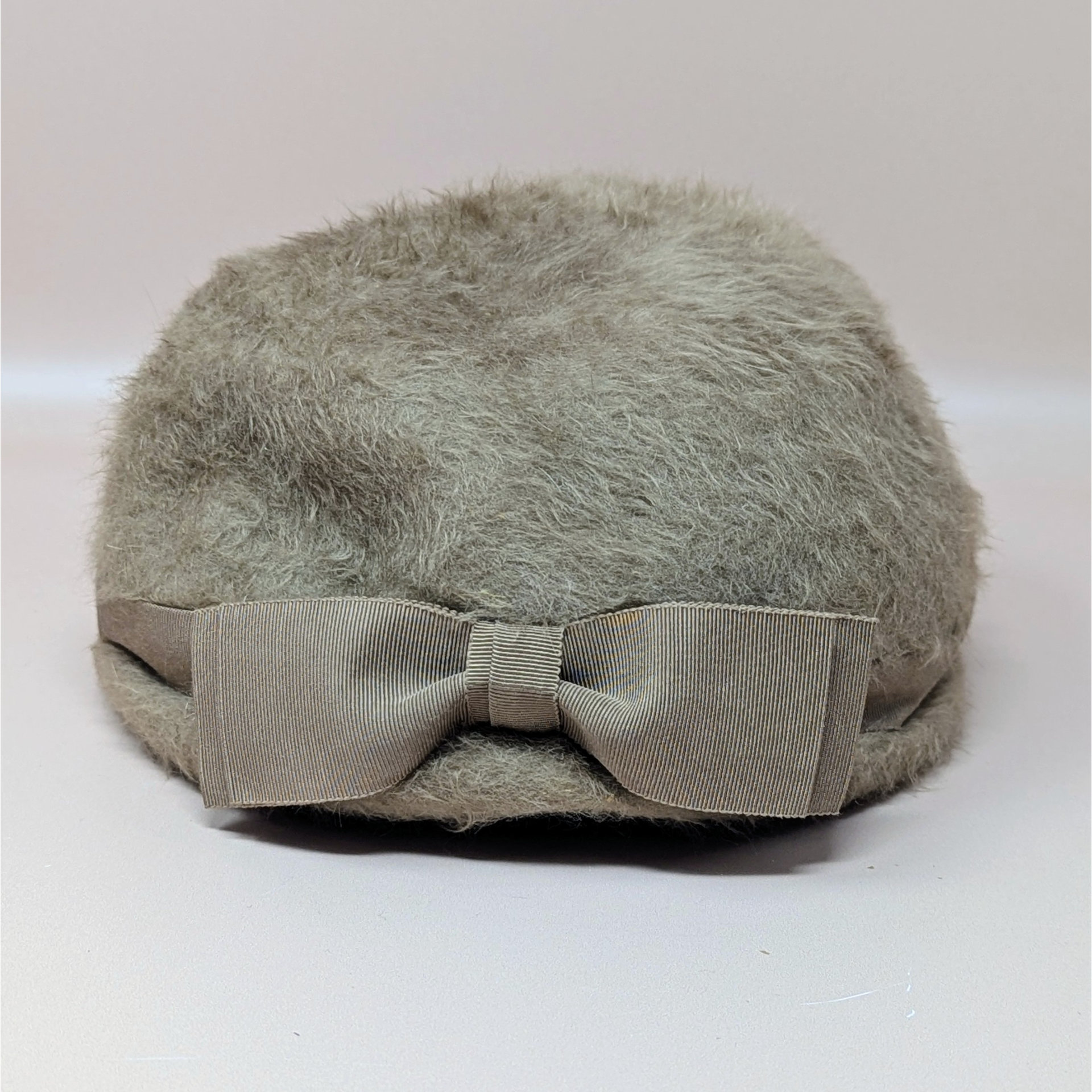 A vintage mid-century BelMar ladies hat made from fuzzy taupe fur felt. The hat features a structured pillbox shape with a matching grosgrain ribbon band and a side bow detail.