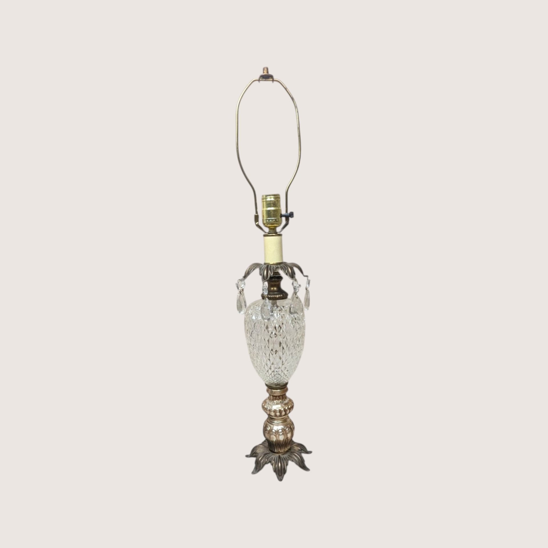 A vintage Hollywood Regency table lamp with a cut glass urn body and hanging crystal glass prisms.