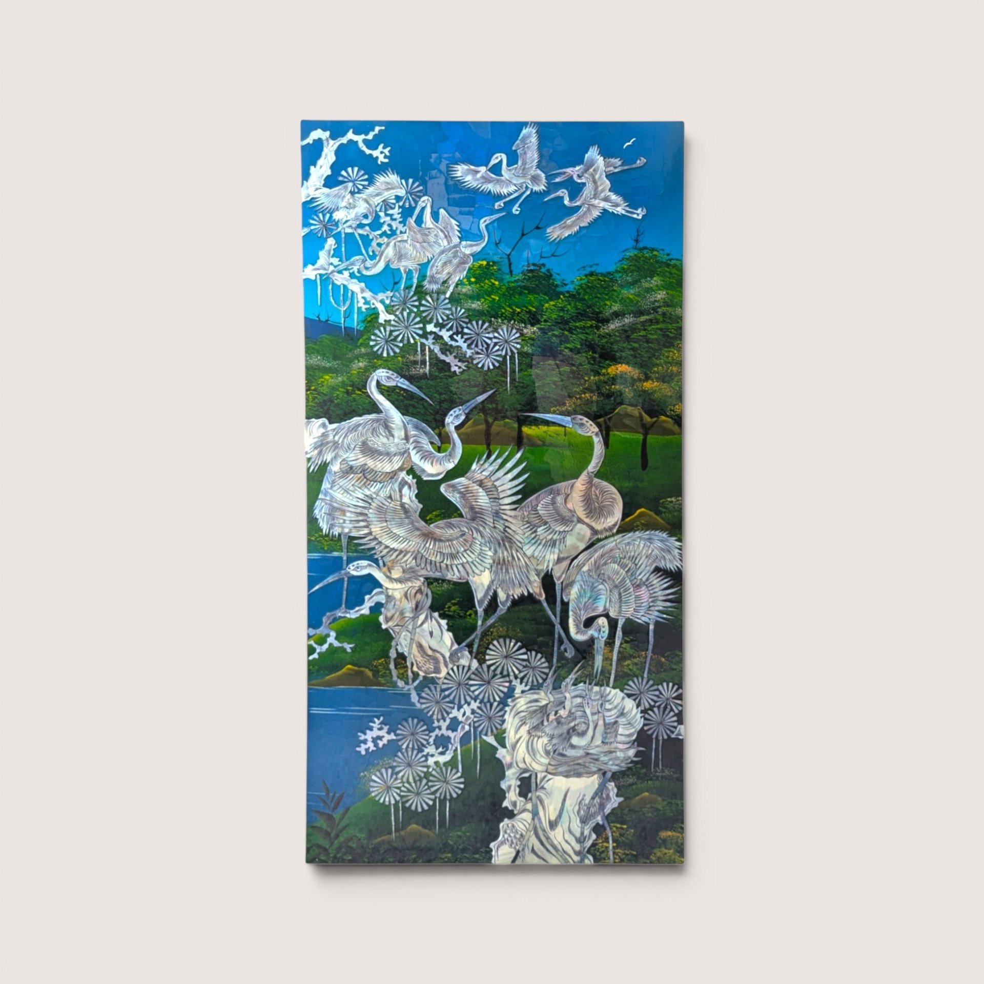 A vintage Asian wall panel showing cranes gather in a lush landscape beside water, inlaid with mother of pearl.