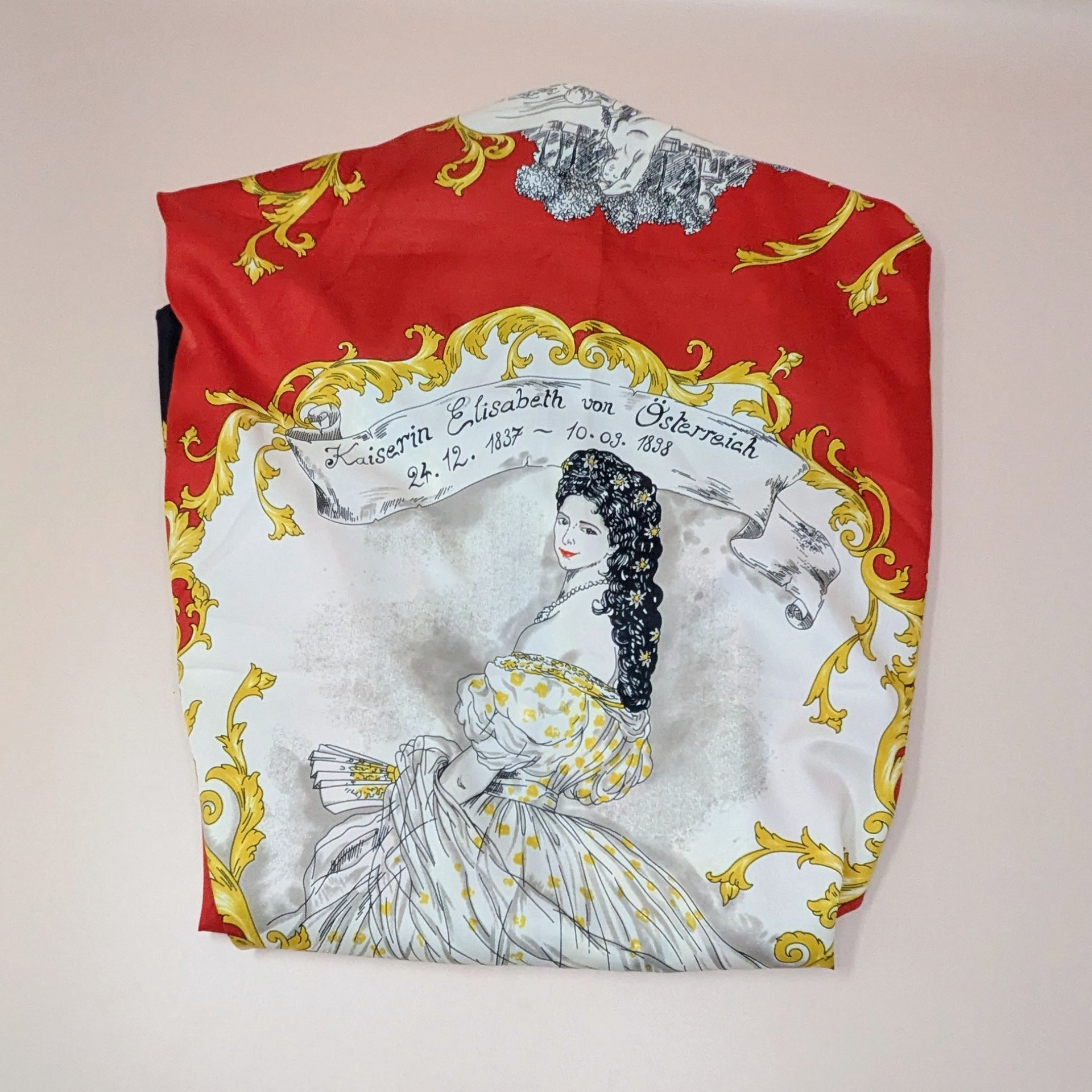 A vintage Striessnig scarf featuring a portrait of Empress Elisabeth of Austria. The design includes a banner with her name and dates, surrounded by intricate gold scrollwork on a bold red and white background.