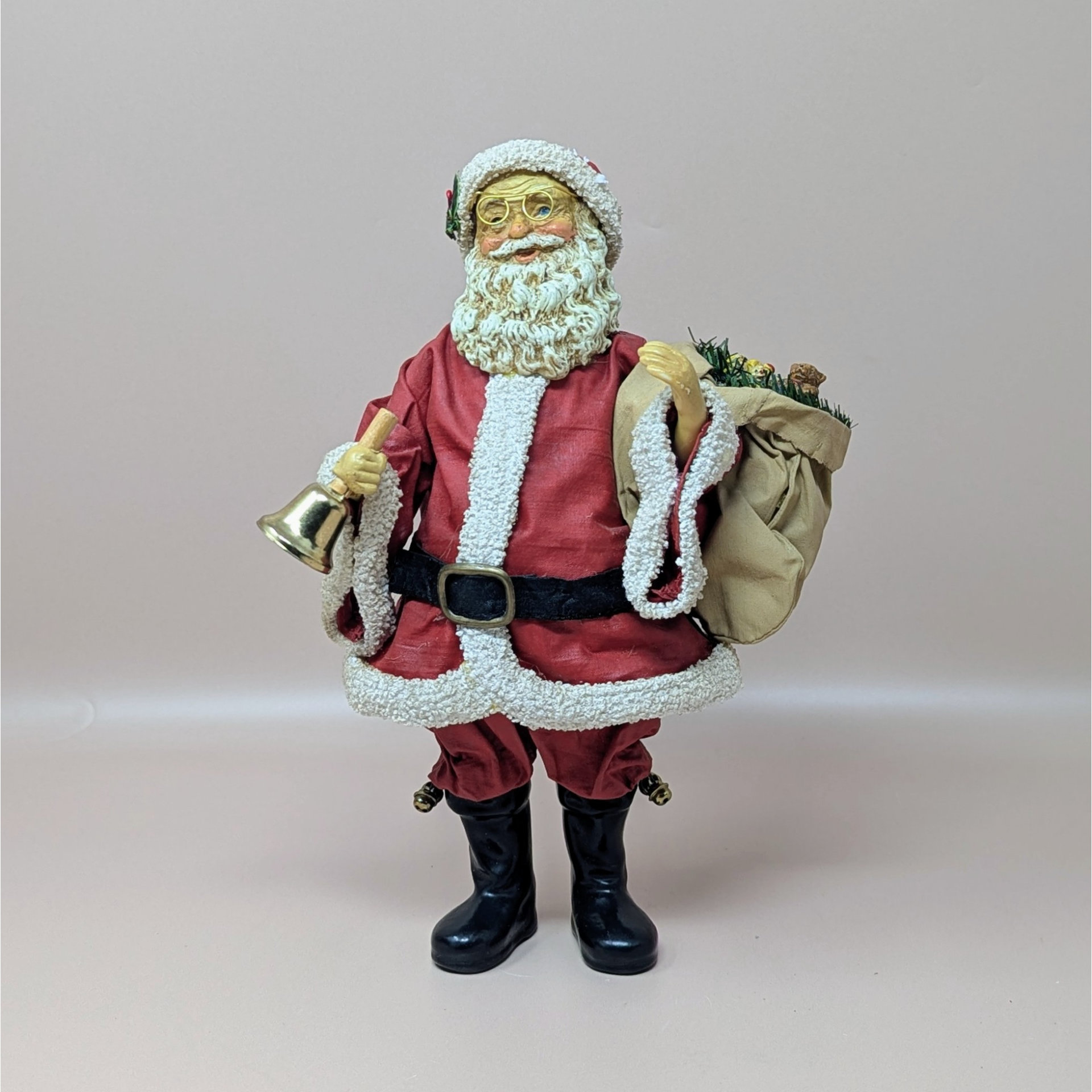 A vintage Santa Claus figure by Midwest Importers, standing 9.5 inches tall. He wears a red coat with white faux fur trim, carries a burlap sack, and holds a gold-tone bell in his hand.