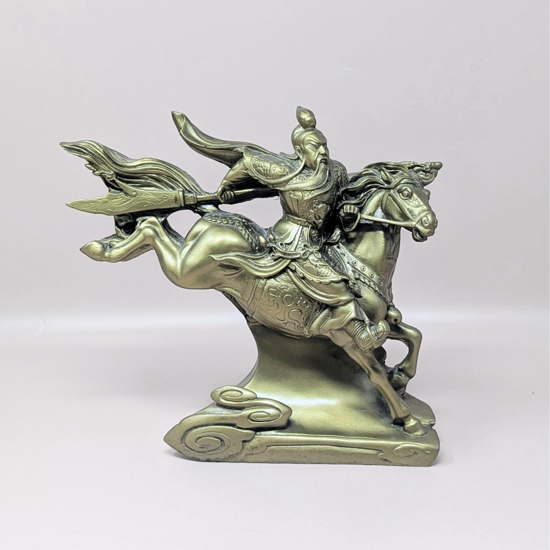 A vintage resin statue of the warrior Guan Yu riding a horse, finished in a metallic gold tone, set atop a sculpted base with stylized clouds.