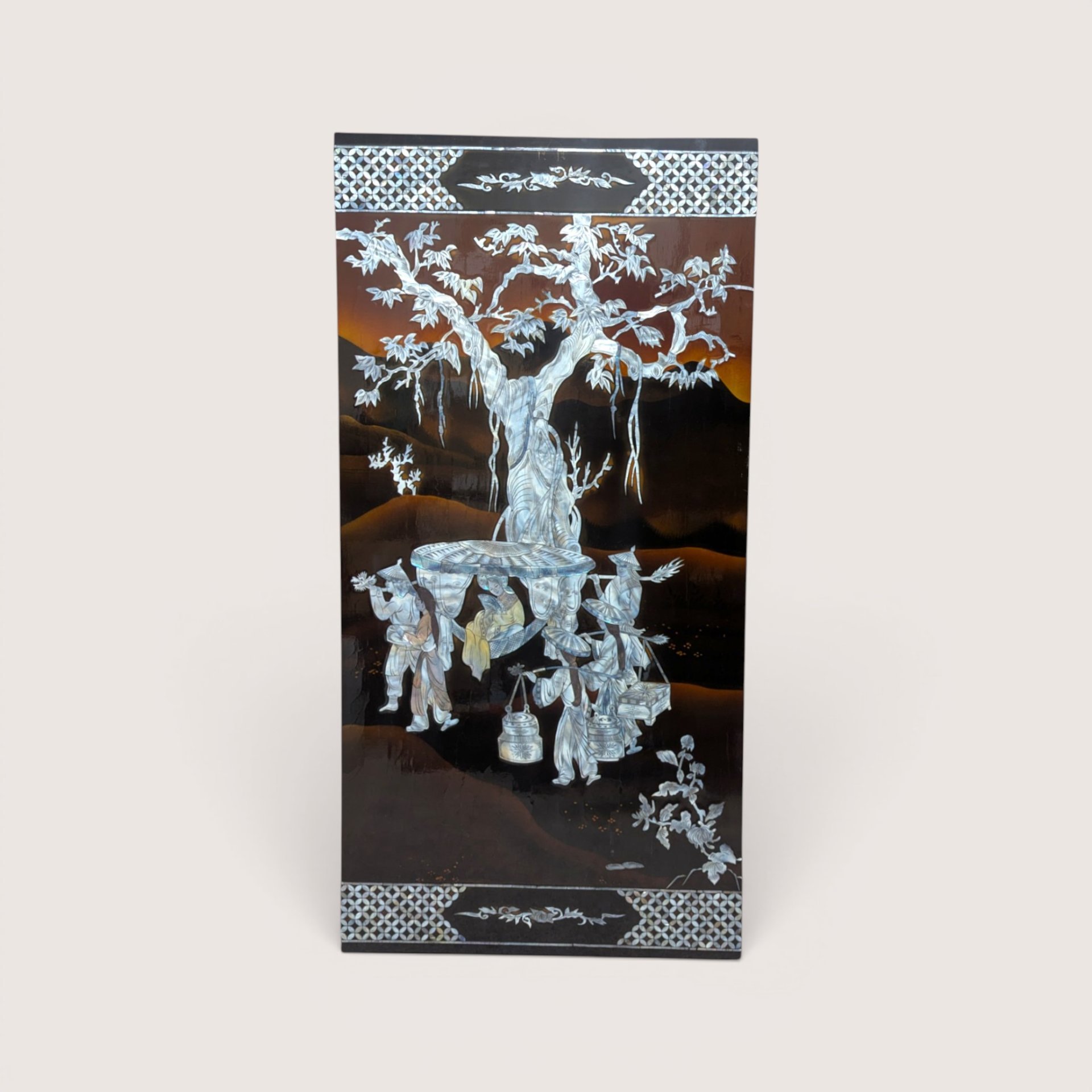 A large rectangular black lacquer wall panel featuring a detailed mother of pearl inlay scene under a large tree.