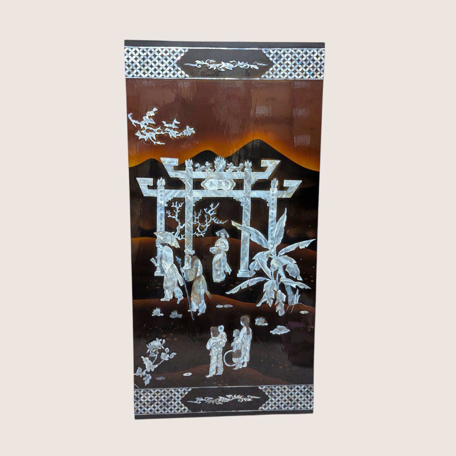 A large rectangular black lacquer wall panel featuring a detailed mother of pearl inlay scene with a grand gateway arch.