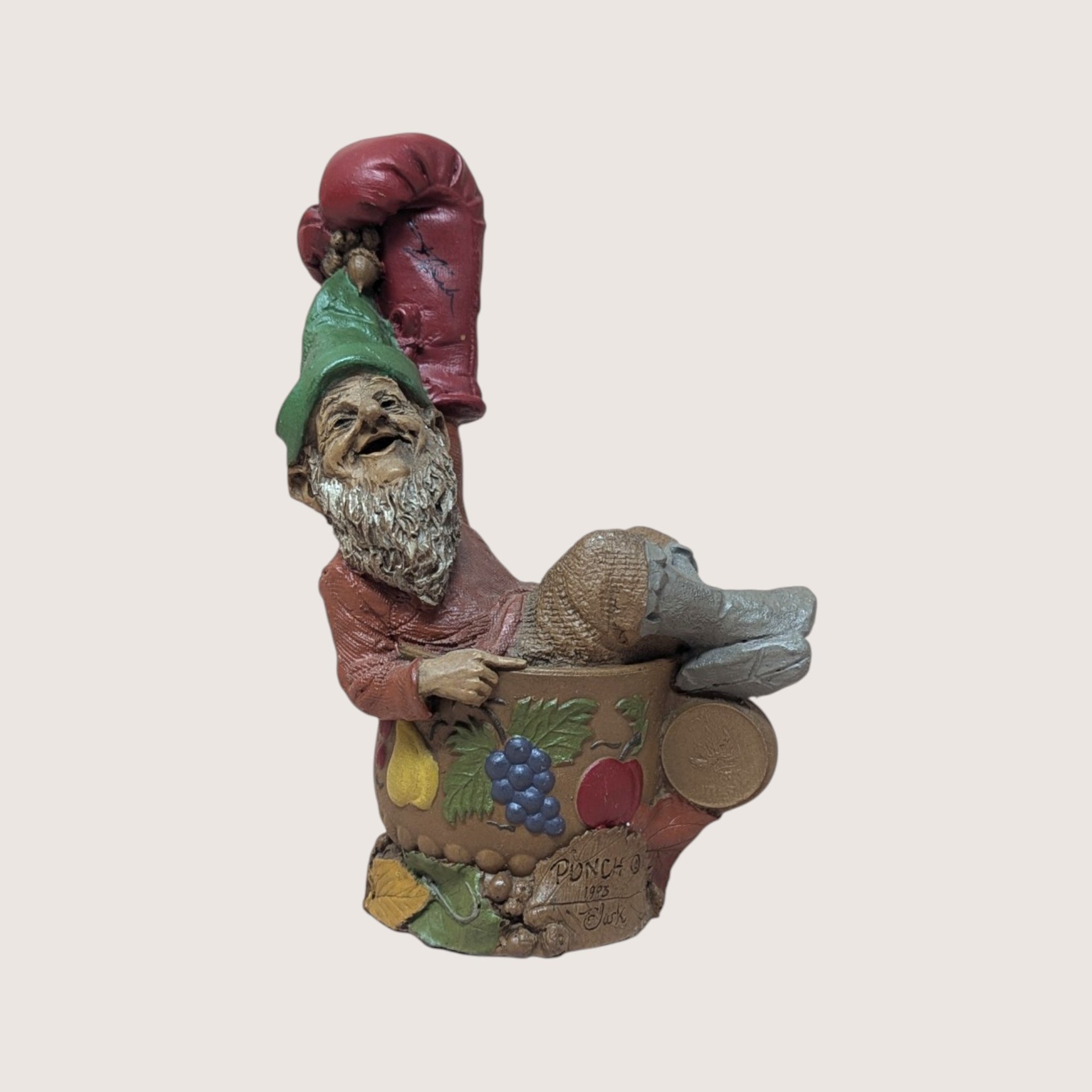 1993 Tom Clark signed Punch gnome figurine inside a fruit bowl wearing a large red boxing glove on a linen background
