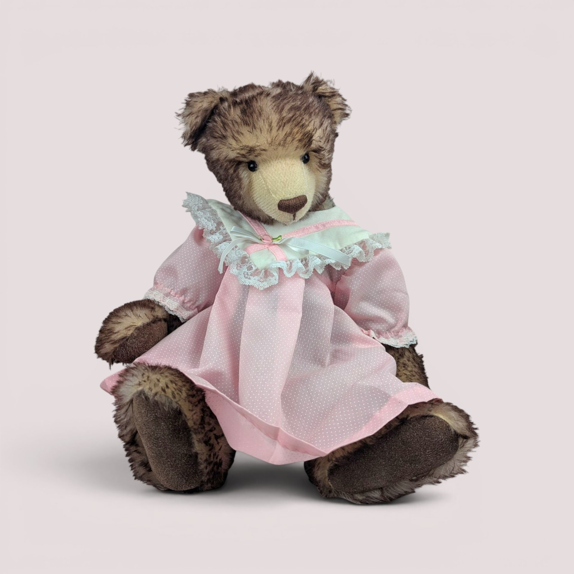 Vintage handmade mohair artist teddy bear by Debra Bistodeau wearing a pink dress with lace trim.