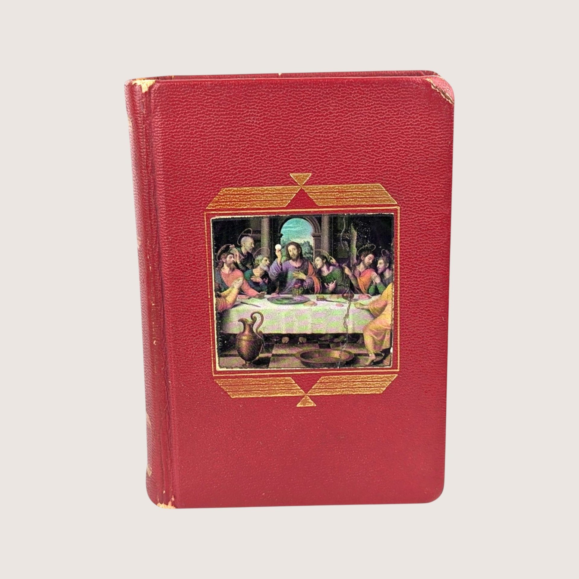 A vintage red textured leatherette catholic missal book featuring a central full color inlay illustration of the last supper.