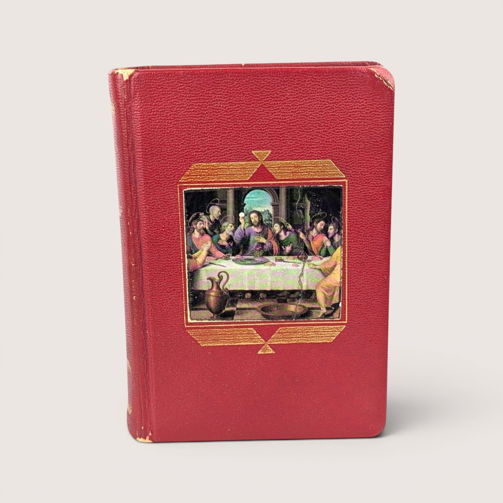 A vintage red textured leatherette catholic missal book featuring a central full color inlay illustration of the last supper.