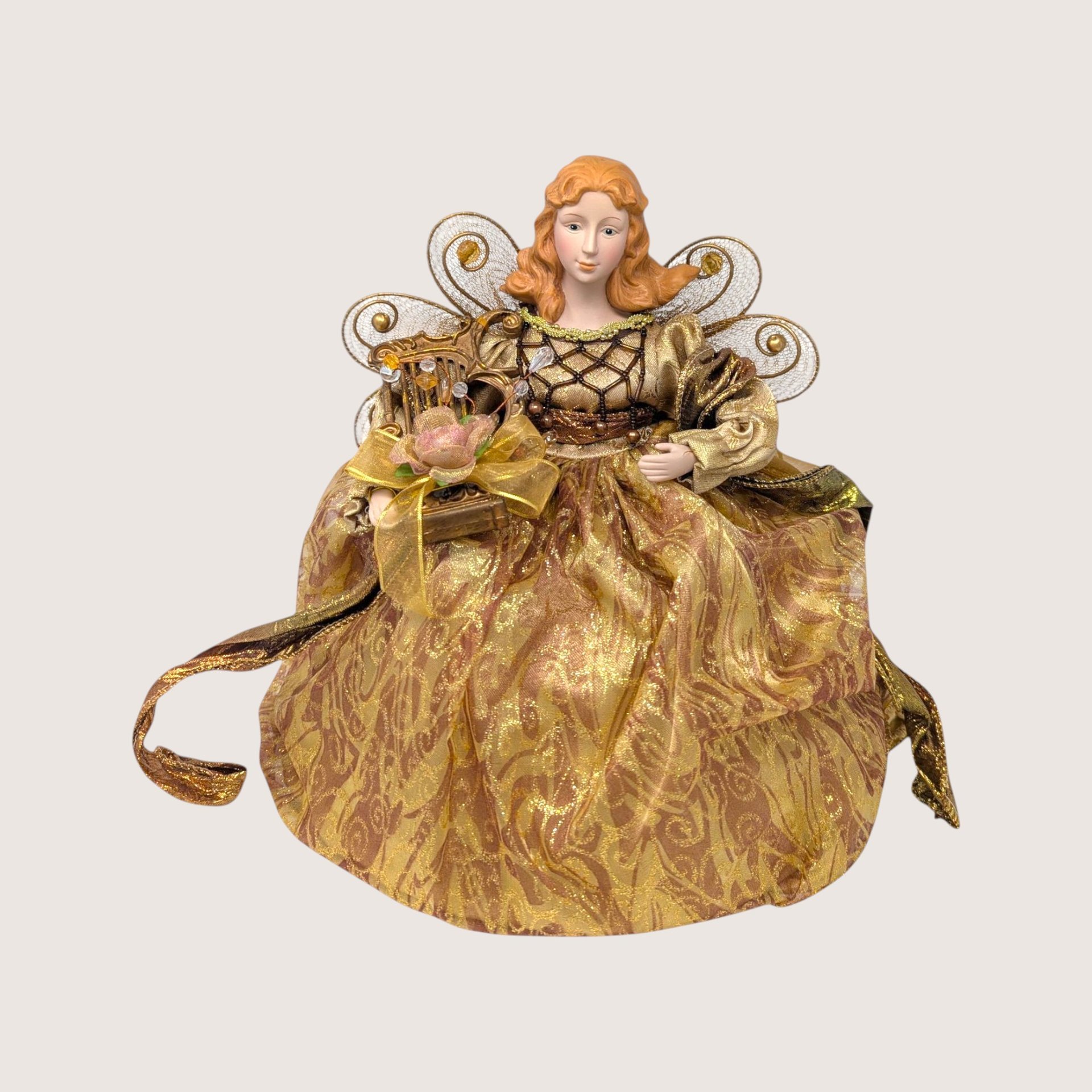 A vintage standing Christmas angel tree topper dressed in a gold metallic gown, holding a miniature harp.
