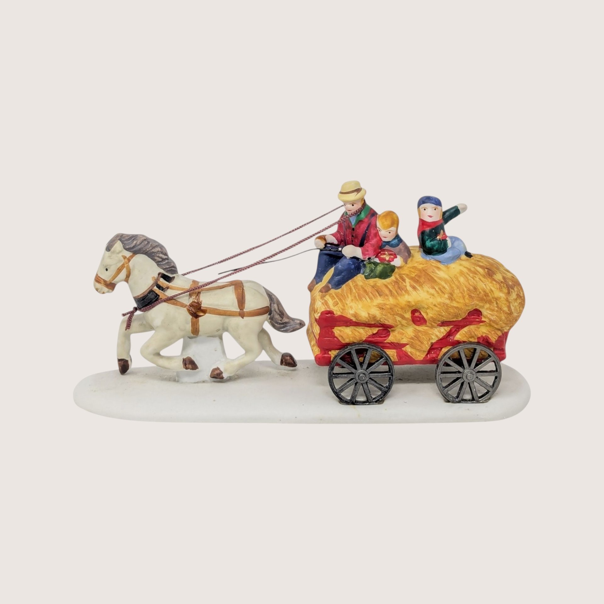 1995 Lemax Dickensvale porcelain figurine of a horse pulling a hayride wagon with three passengers on a linen background