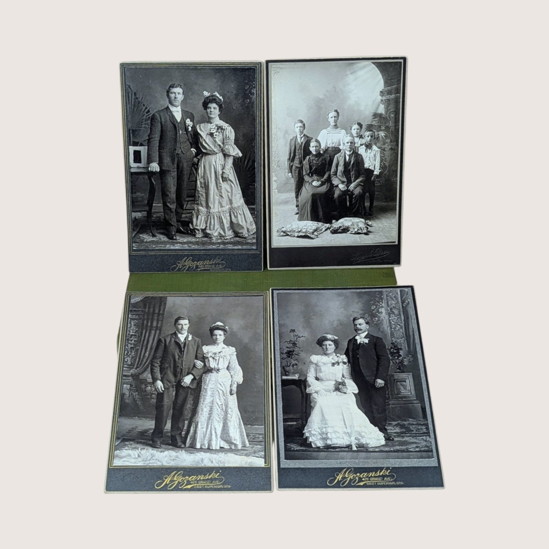 Four antique Victorian cabinet card portraits displayed on a soft pink background. The monochrome photographs feature formal wedding couples in period attire and a family group, with gold embossed studio text reading A. Gozanski West Superior WIS.