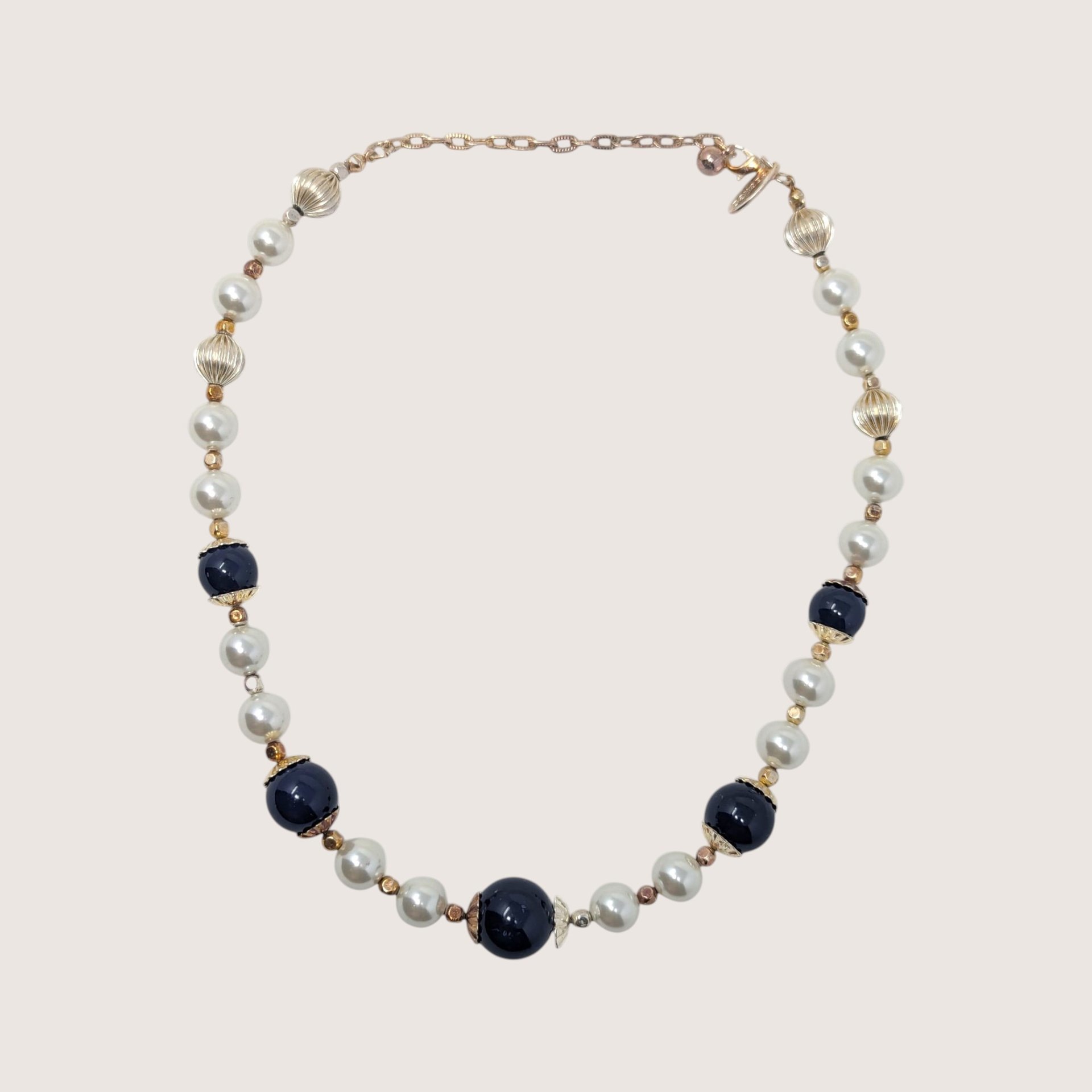 Vintage George statement necklace with dark blue glass beads, white pearls, and gold accents on a linen background