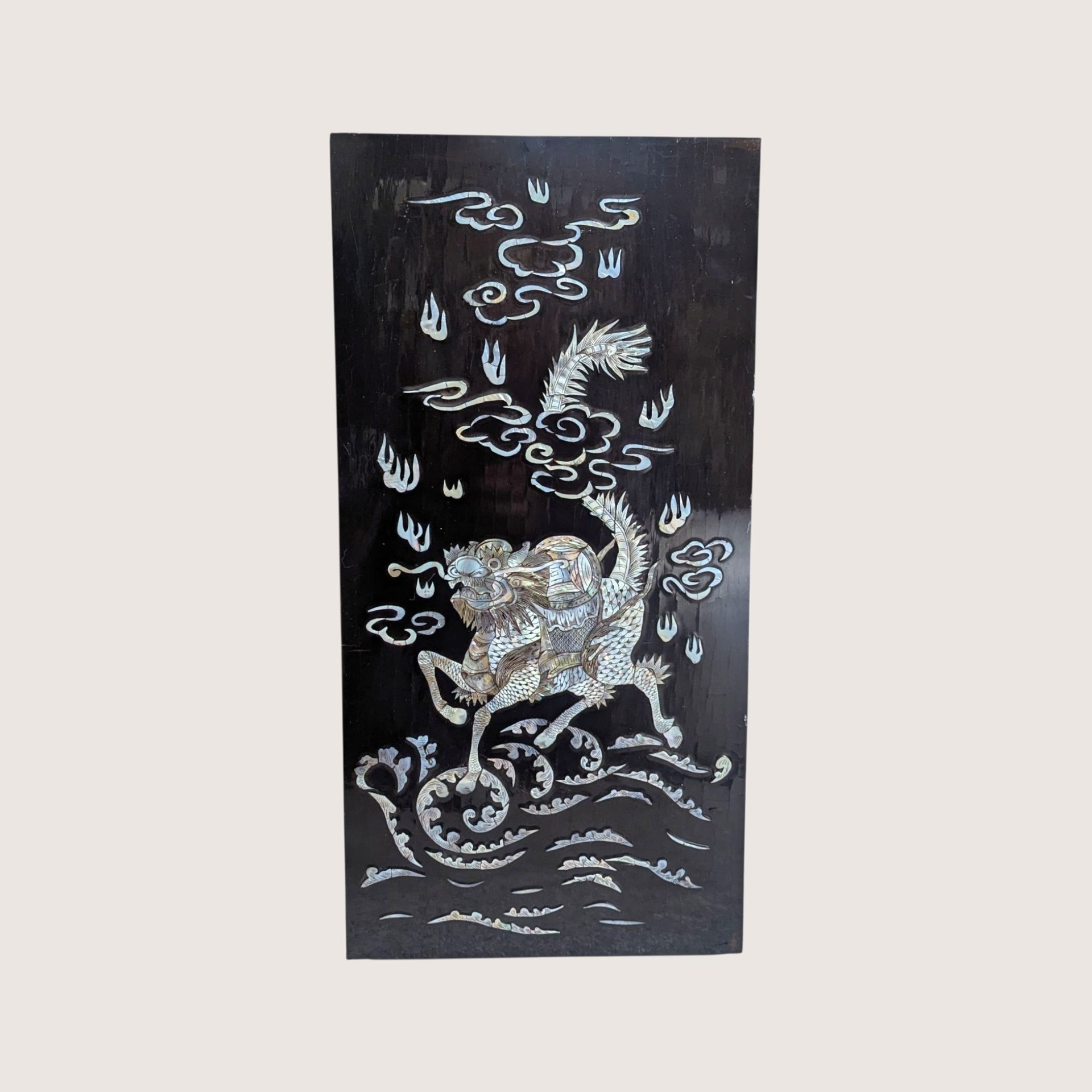 Vintage Asian black lacquer wood wall panel with iridescent mother of pearl inlay depicting a qilin on a linen background