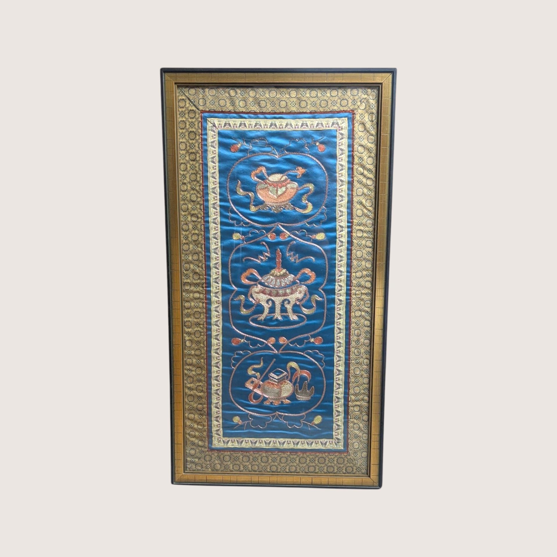 Vintage framed Chinese silk embroidery panel with three urn and censer motifs on a blue background and a linen backdrop