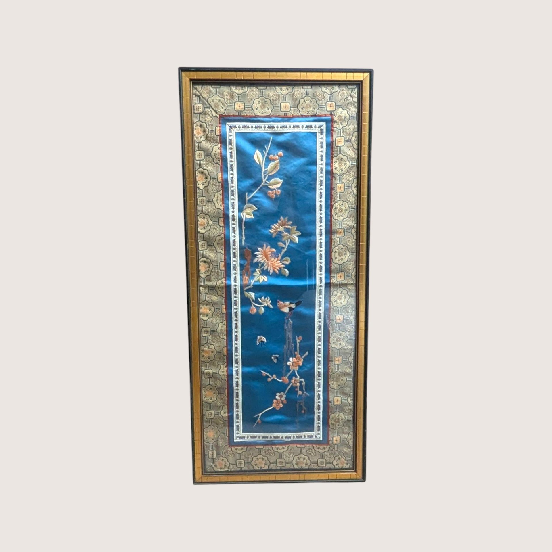Vintage framed Chinese silk embroidery panel with a bird and chrysanthemums on a blue background and a linen backdrop