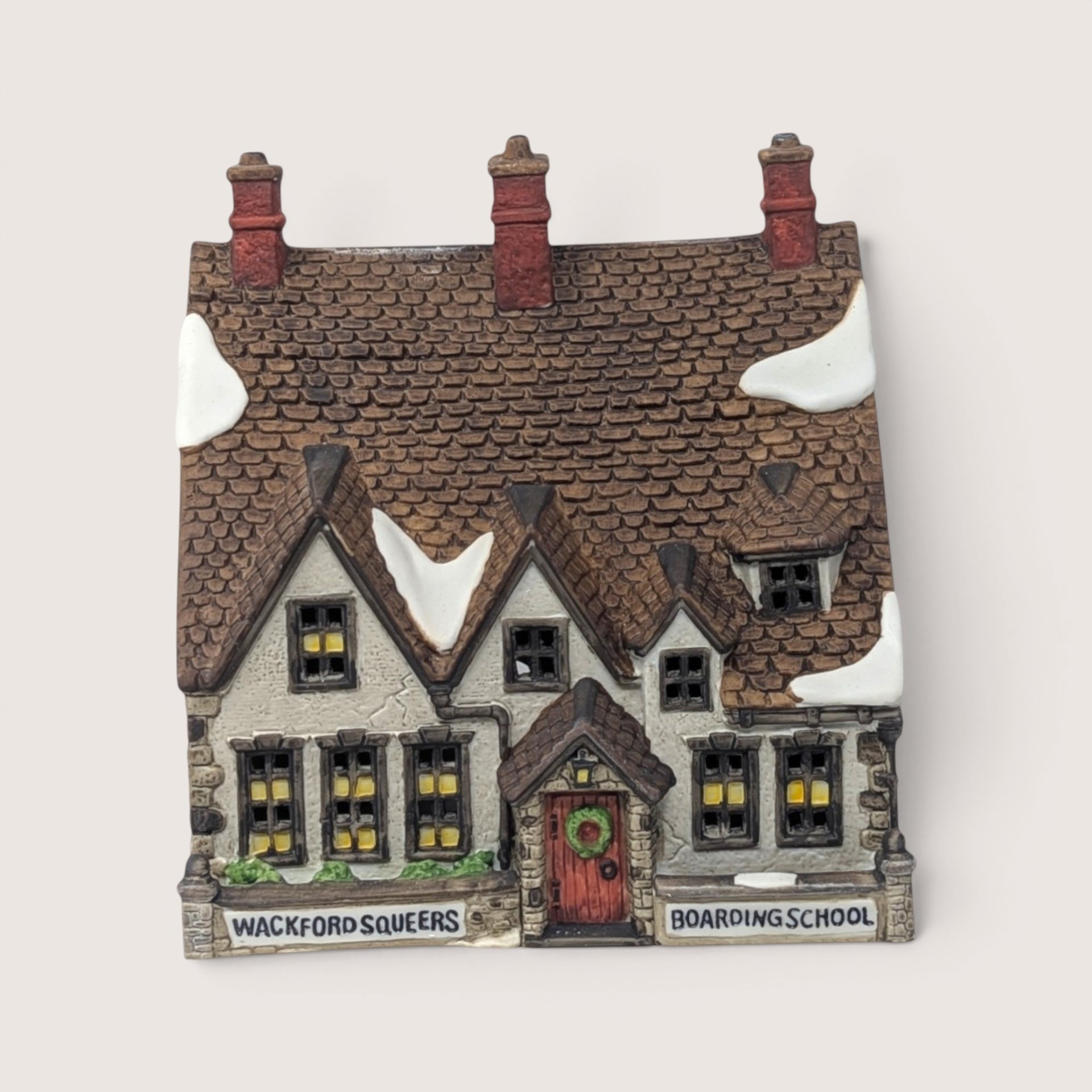 A handpainted porcelain Dept 56 Wackford Squeers Boarding School building on a linen background