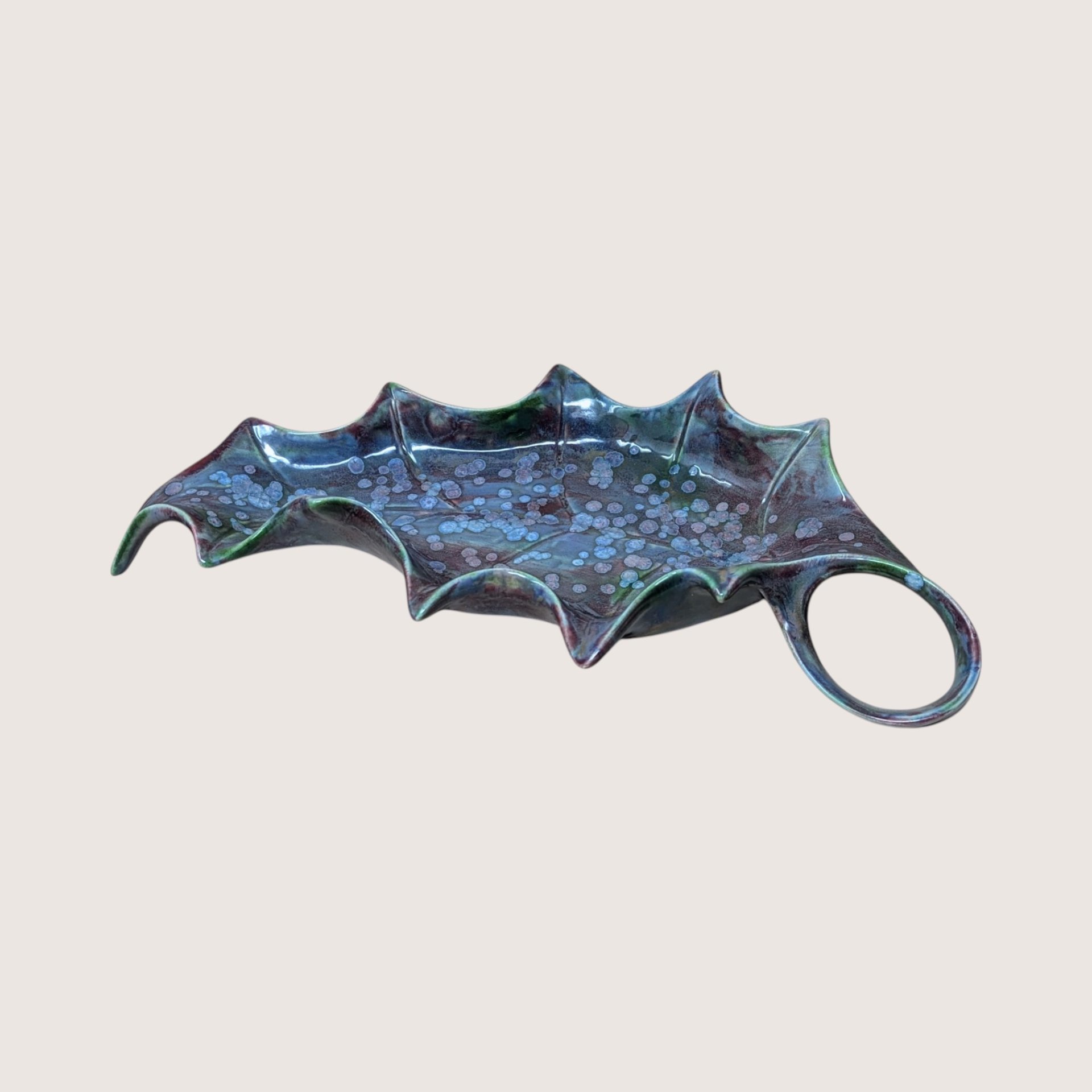 Vintage mid century handmade ceramic holly leaf dish featuring a striking blue and purple reactive drip glaze with an integrated loop handle.