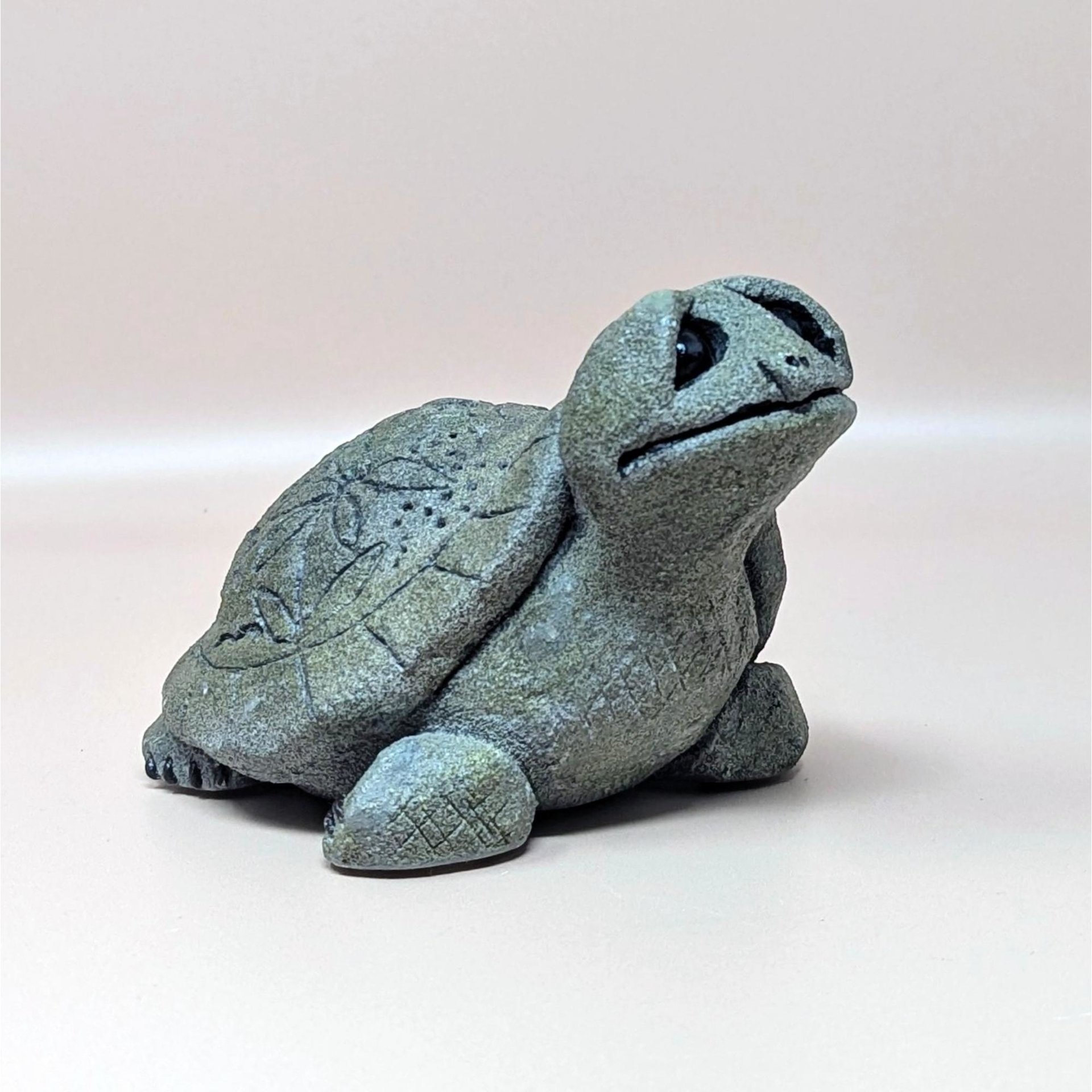 A 1993 Lou Ranken Slowpoke turtle figurine by Hallmark on a soft pink background. The highly textured gray resin sculpture shows a charming turtle looking upward with large expressive black eyes and a faintly etched leaf pattern on its shell.