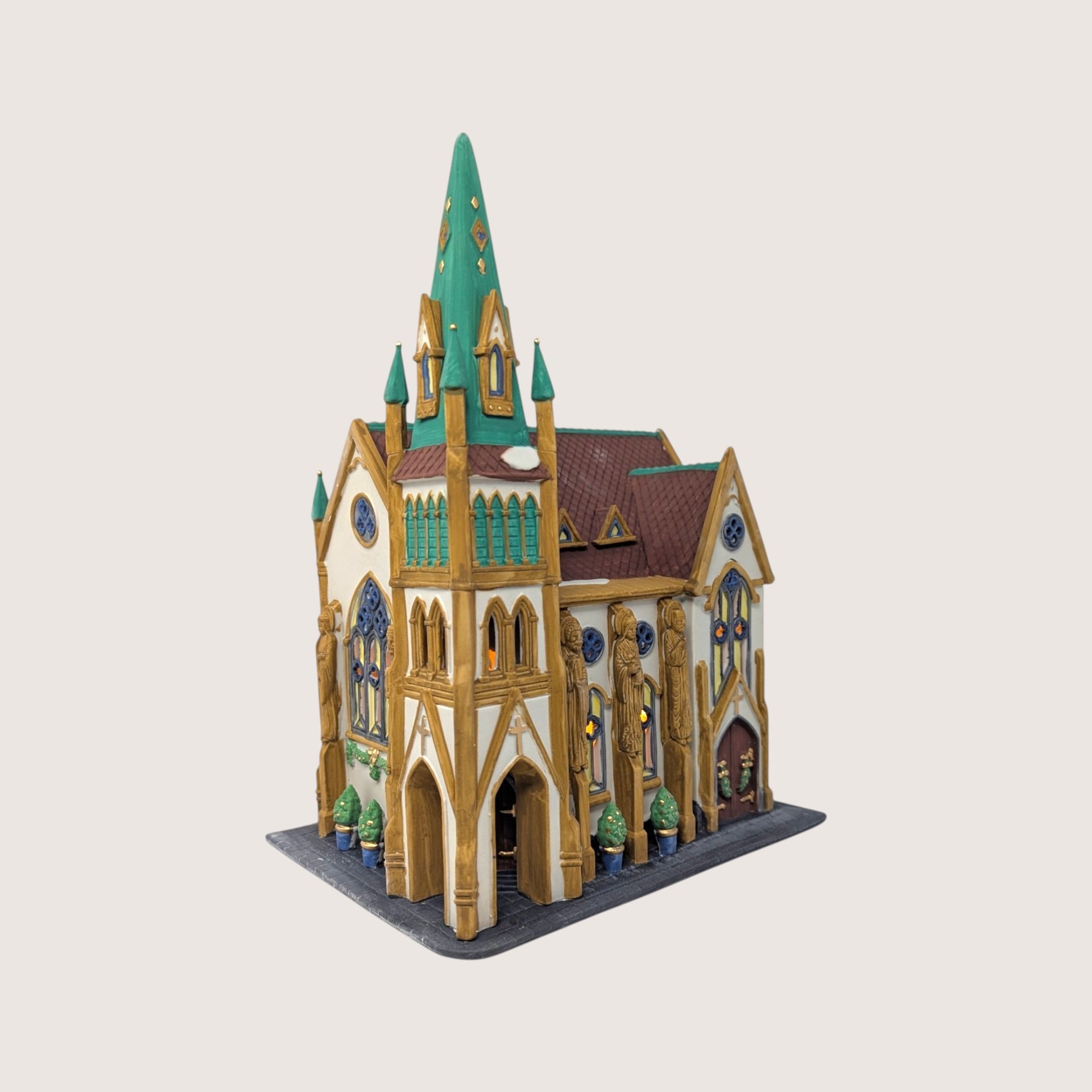 A handpainted porcelain Dept 56 All Saints Corner Church building on a linen background