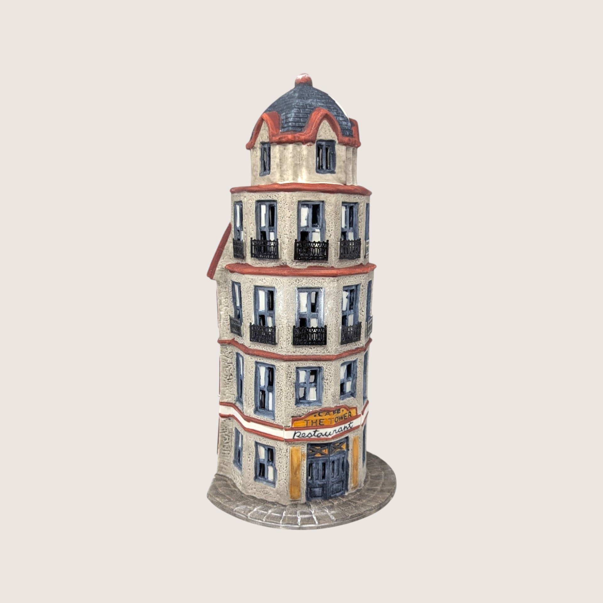 A handpainted porcelain Dept 56 The Tower Cafe flatiron style building on a linen background