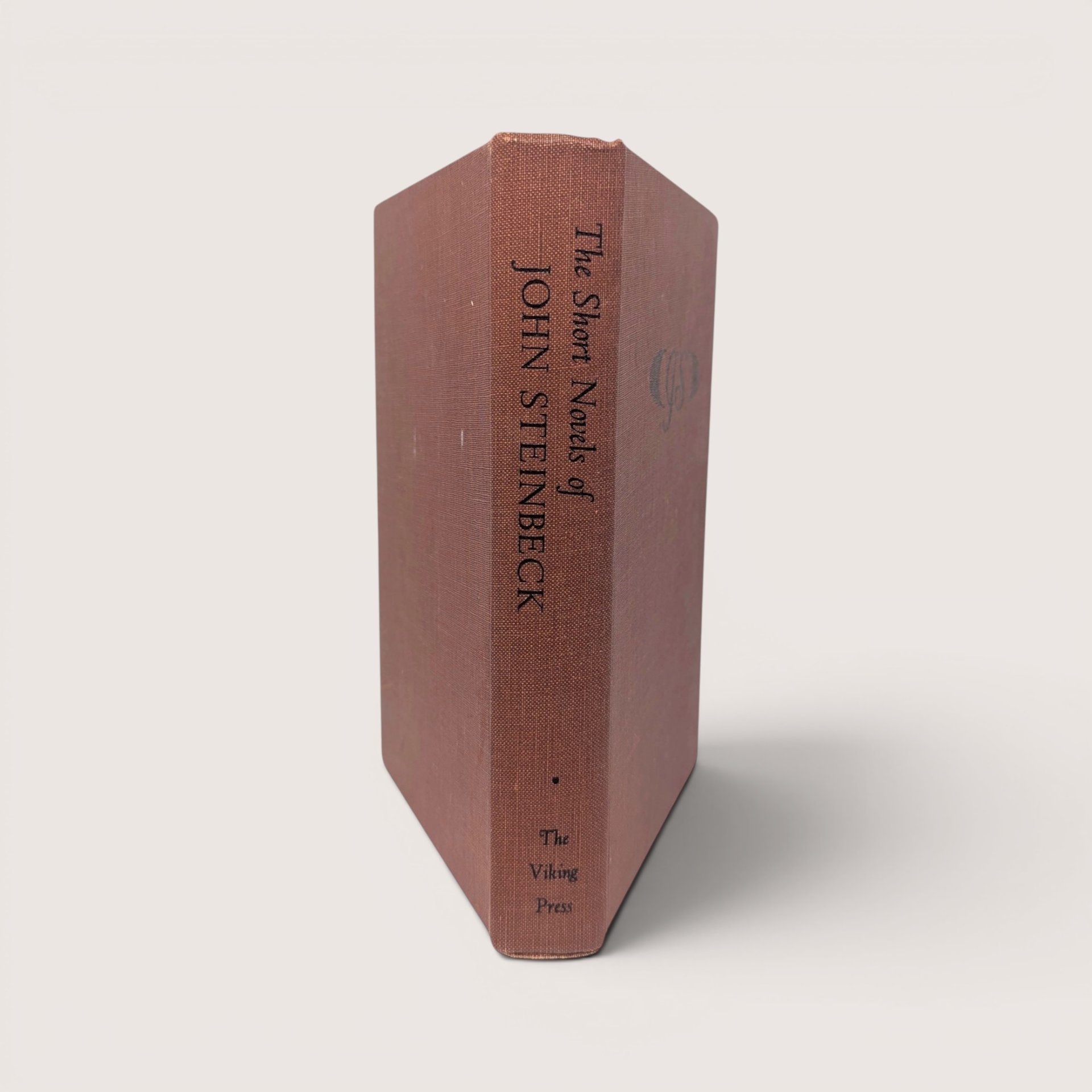 The textured brown cloth spine of a vintage hardcover book with black text on a plain background