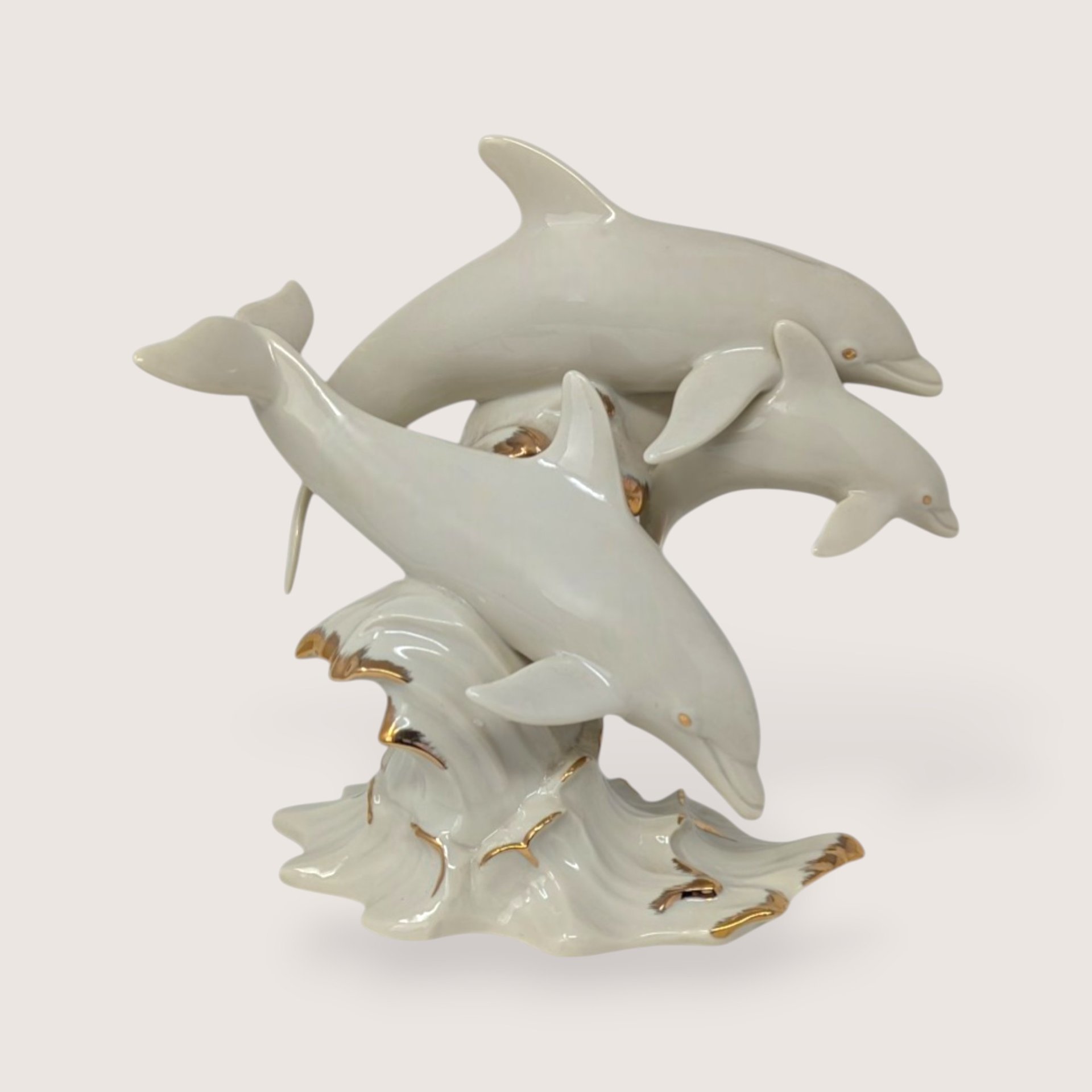 Vintage Lenox ivory cream porcelain sculpture of three dolphins leaping over gold gilded ocean waves.