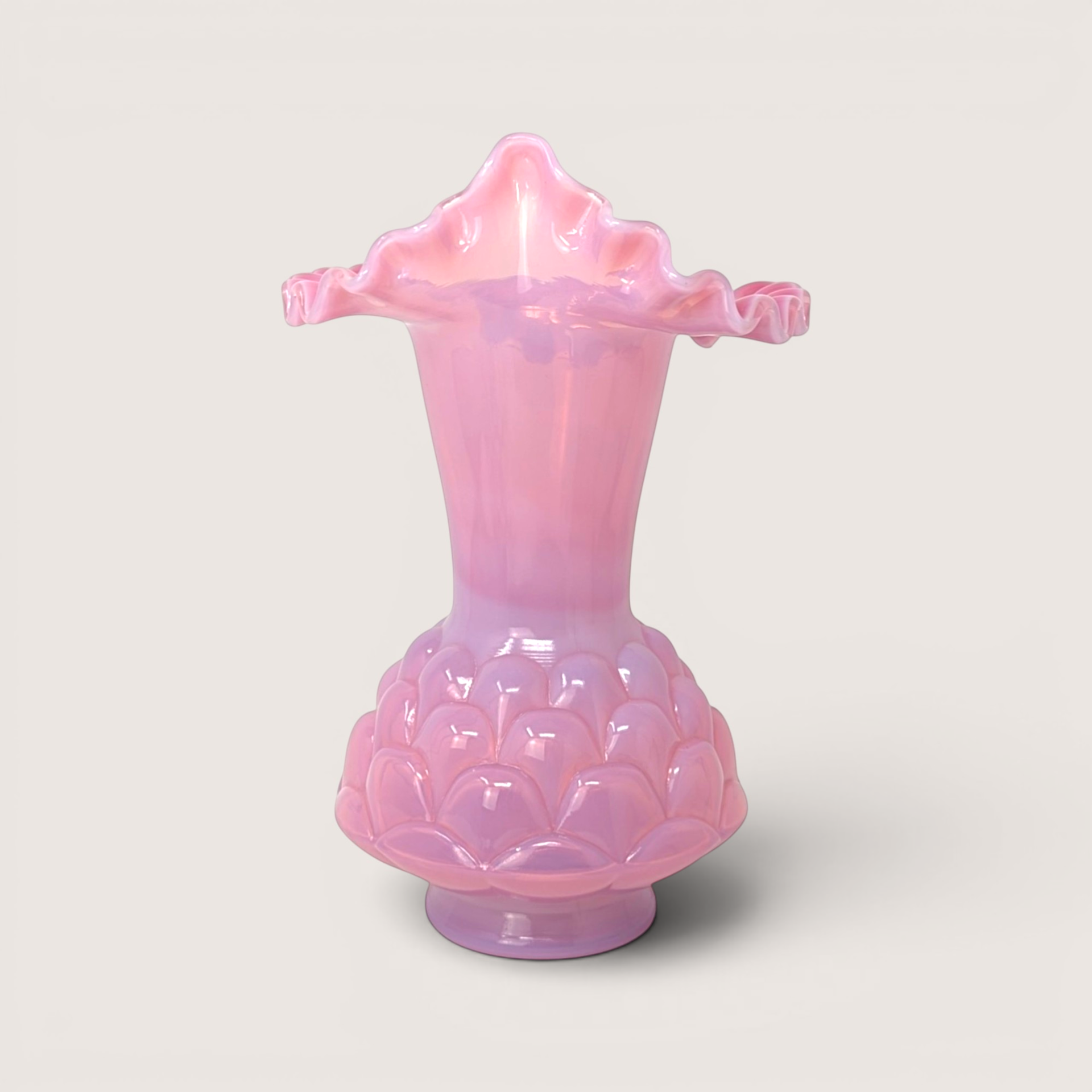 A pink Fenton plum opalescent Jacqueline vase with a ruffled rim, set against a neutral cream background.