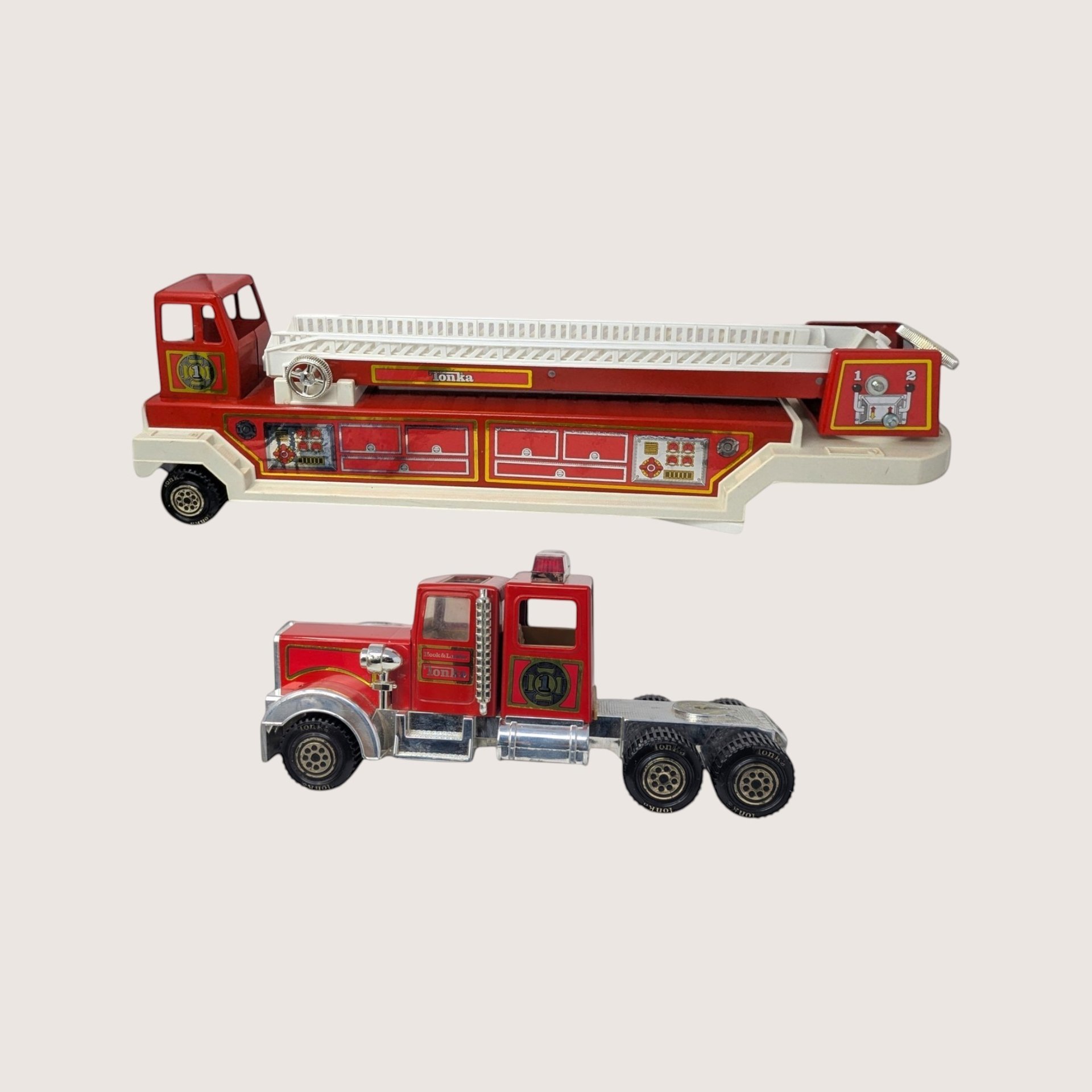 A vintage red and white two piece Tonka hook and ladder semi firetruck on a plain cream background