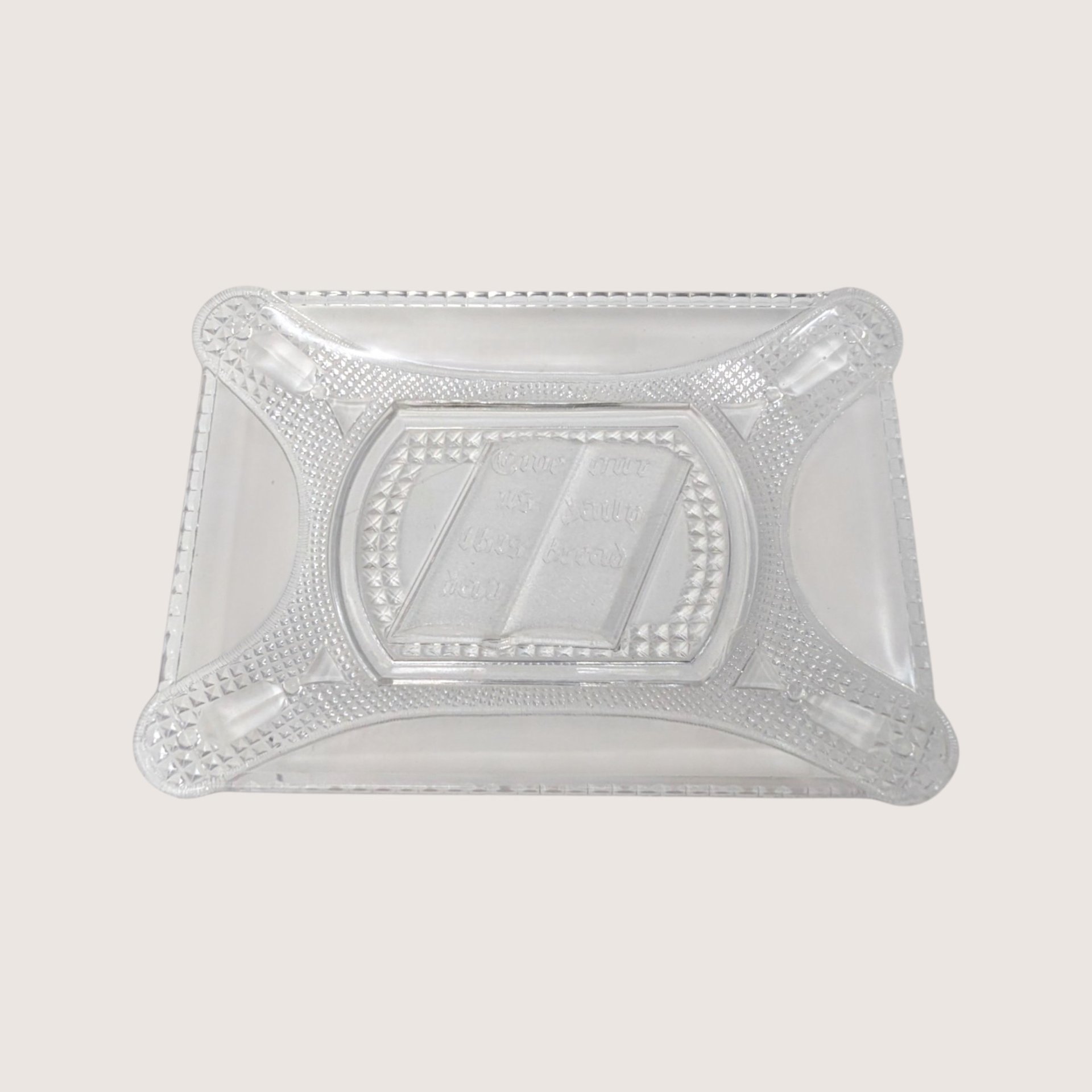 Clear rectangular pressed glass bread plate featuring an open Bible design in the center on a solid background.