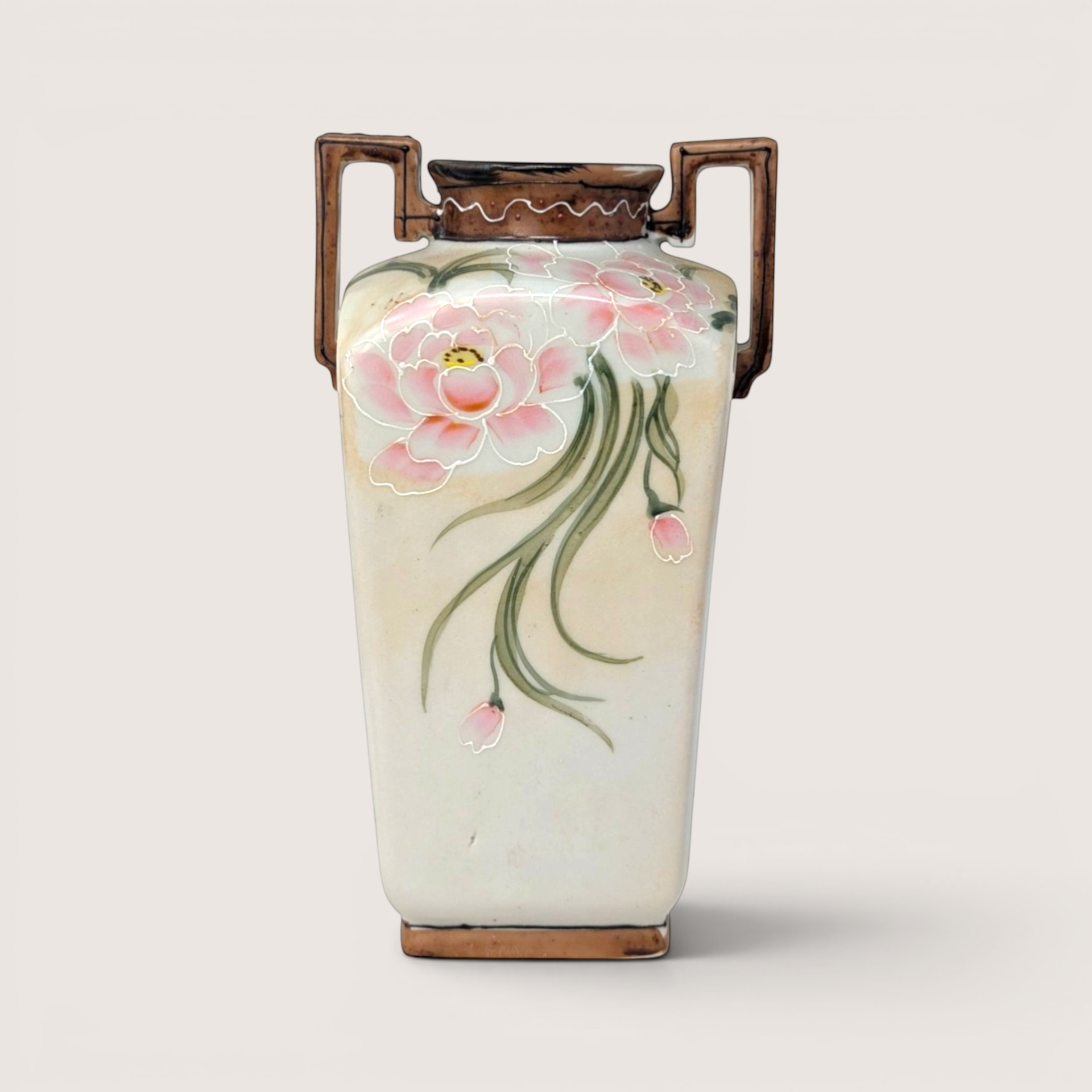 Hand painted porcelain vase featuring large pink blossoms trailing green leaves and two geometric handles on a solid background.