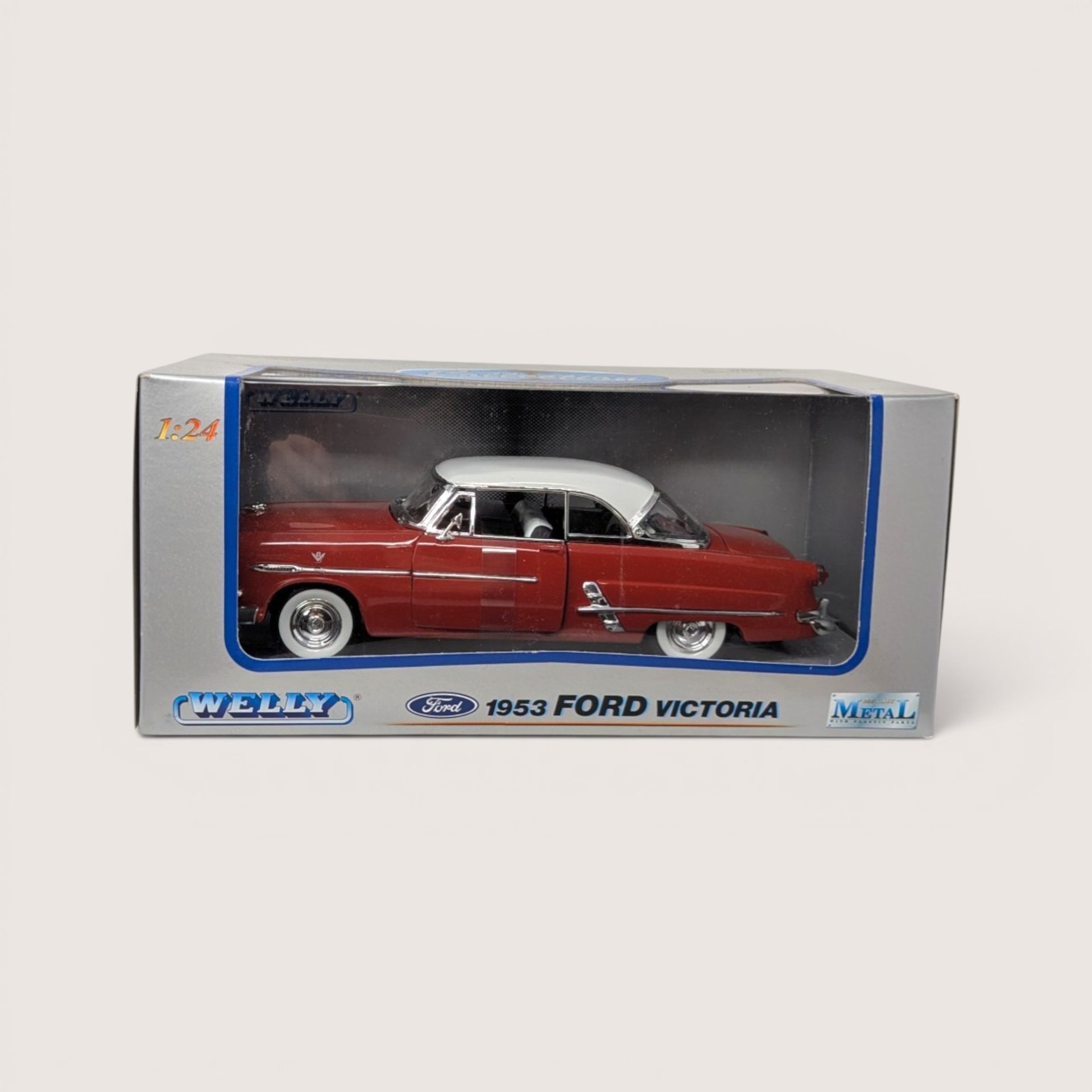 A red 1953 Ford Victoria toy car with a white roof sealed inside its original gray and blue Welly box