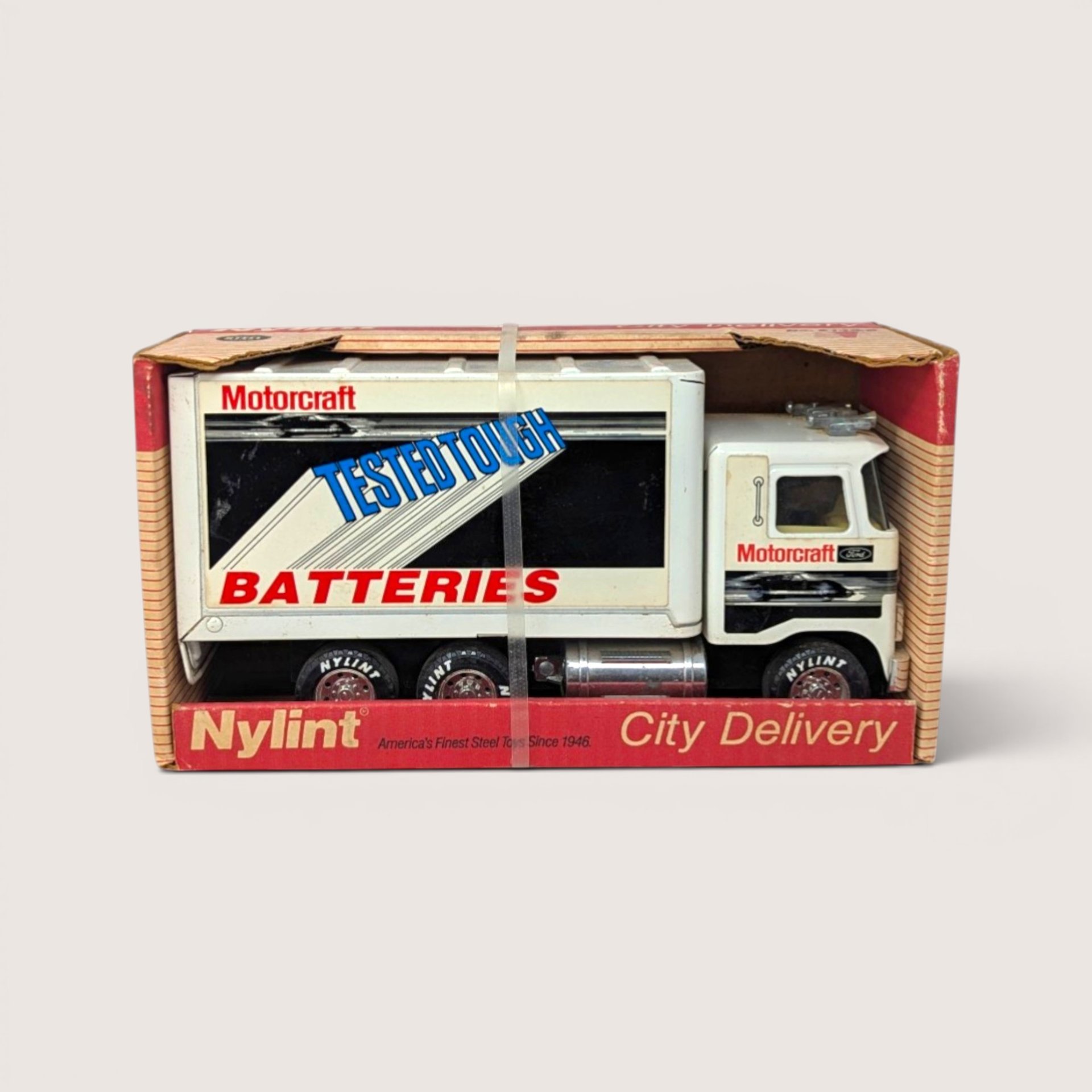 A vintage white Nylint Motorcraft Batteries toy delivery truck in its original red cardboard display box