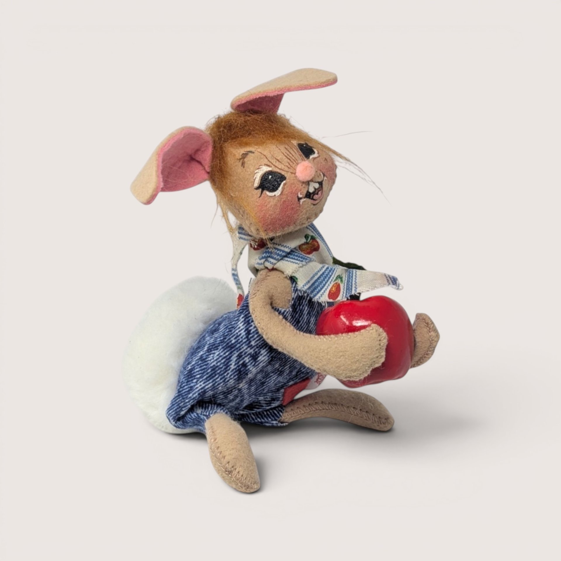 Annalee felt boy bunny doll dressed in denim overalls with an apple patterned scarf holding a large red apple.