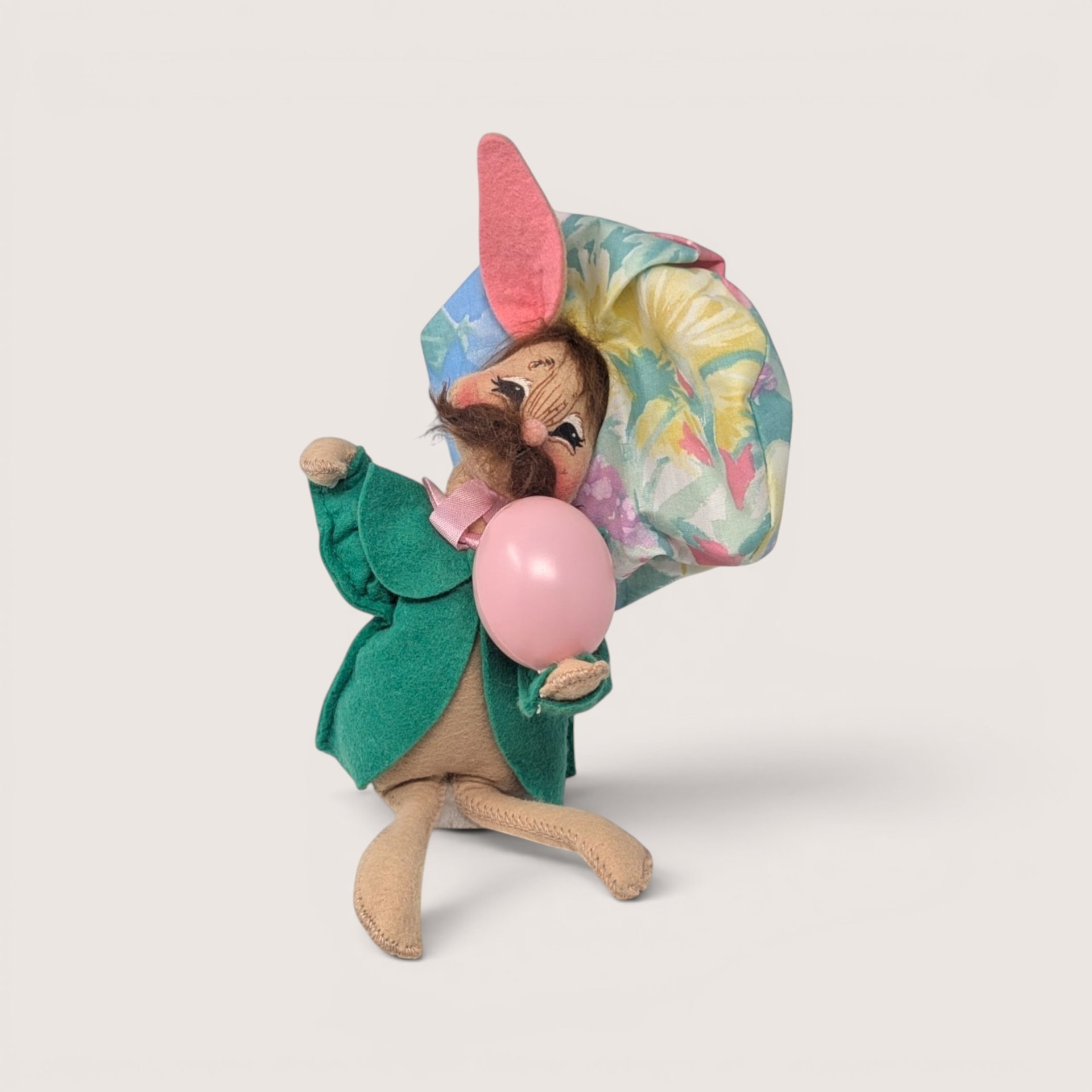 Annalee felt artist bunny doll with a mustache, floral beret, and green smock holding a pink egg accessory.
