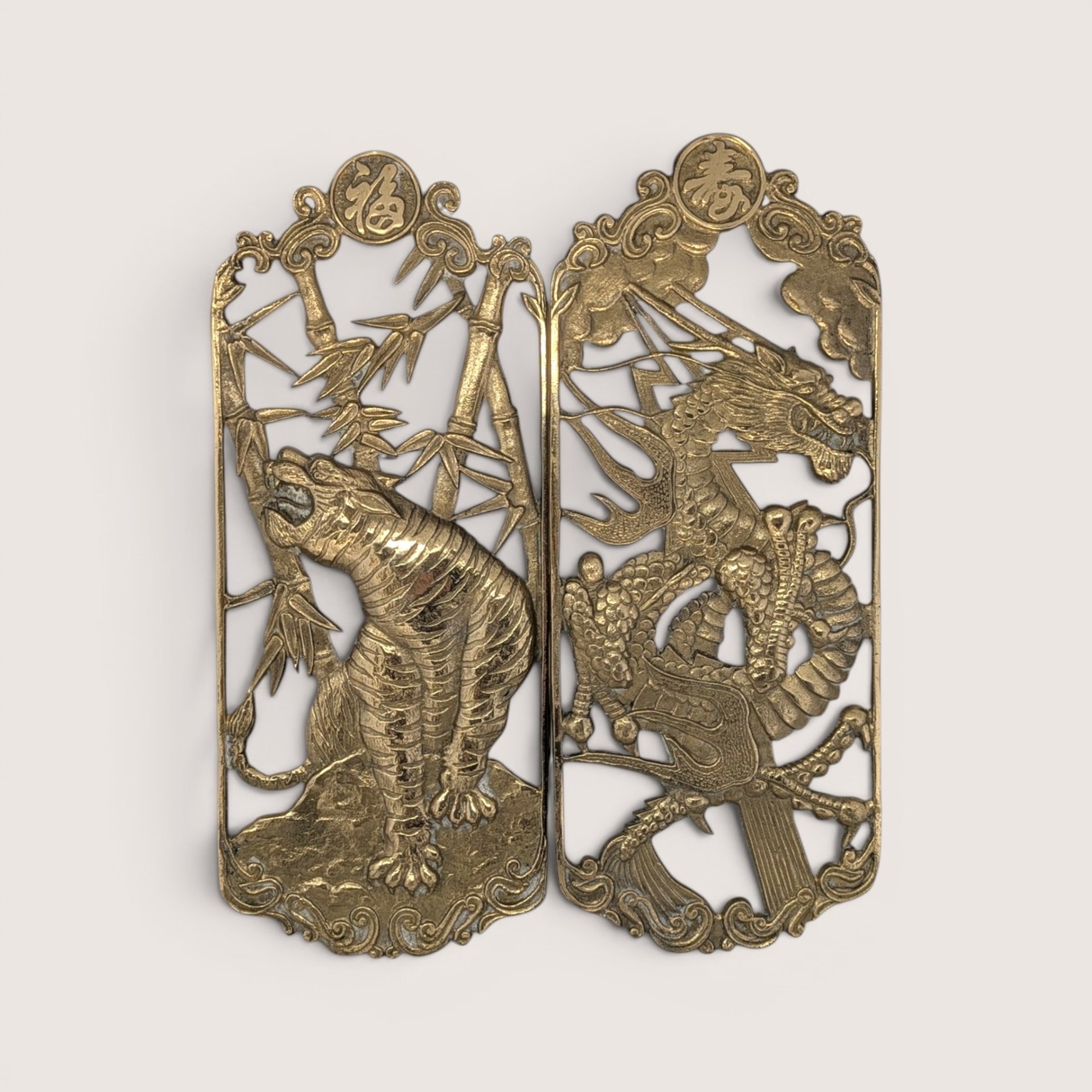 Vintage pierced brass rectangular openwork wall plaques featuring a stylized tiger in bamboo and a detailed dragon.