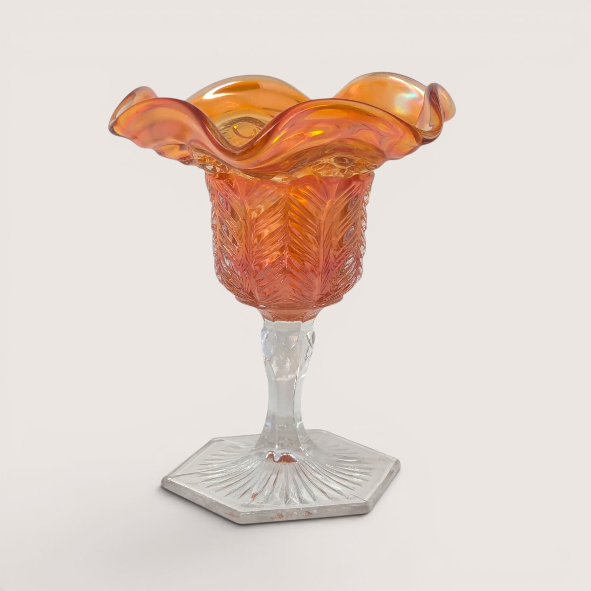 Vintage Cambridge Inverted Feather marigold carnival glass compote with ruffled rim and hexagonal starburst base.