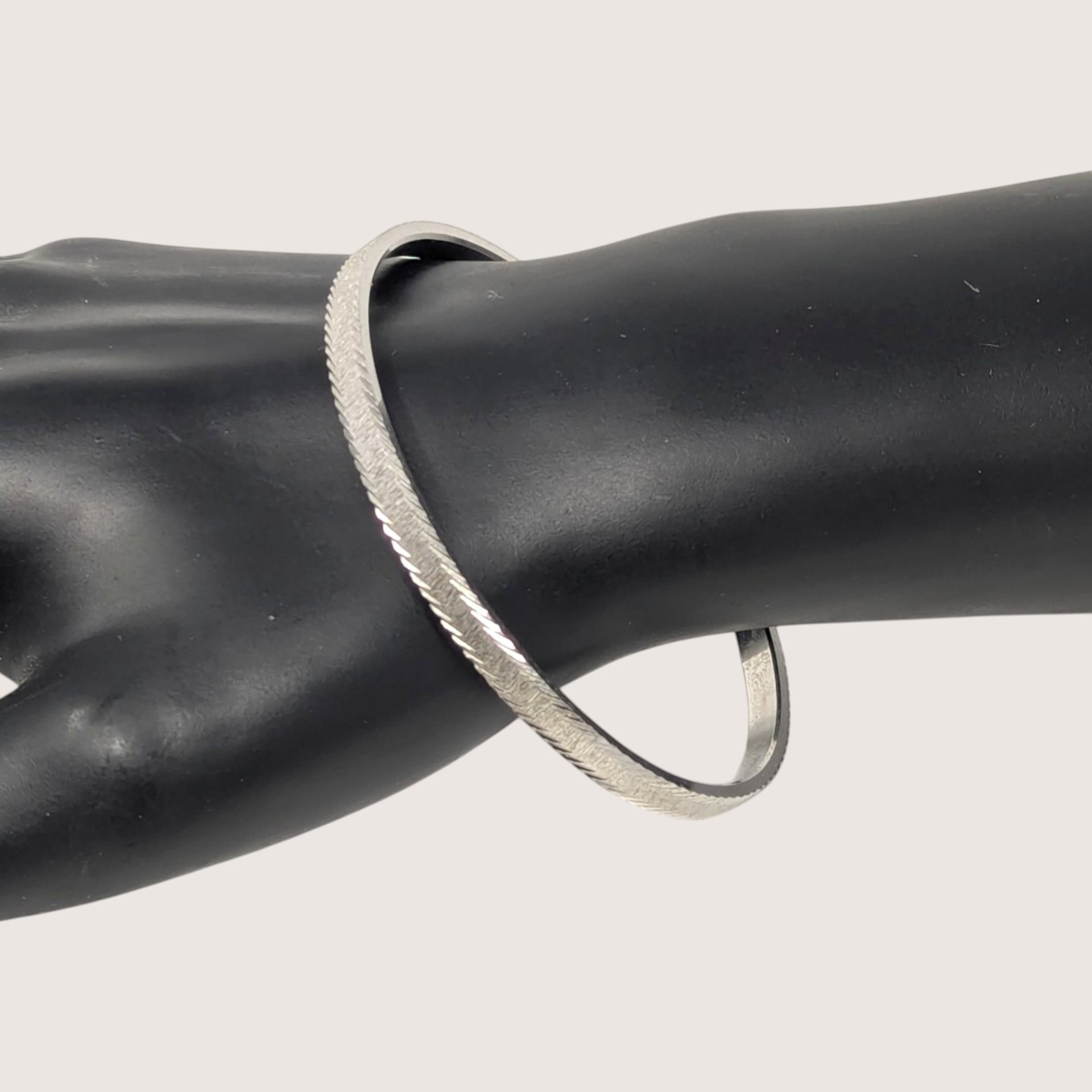 Vintage signed Trifari silver tone textured bangle bracelet with an engraved pattern.