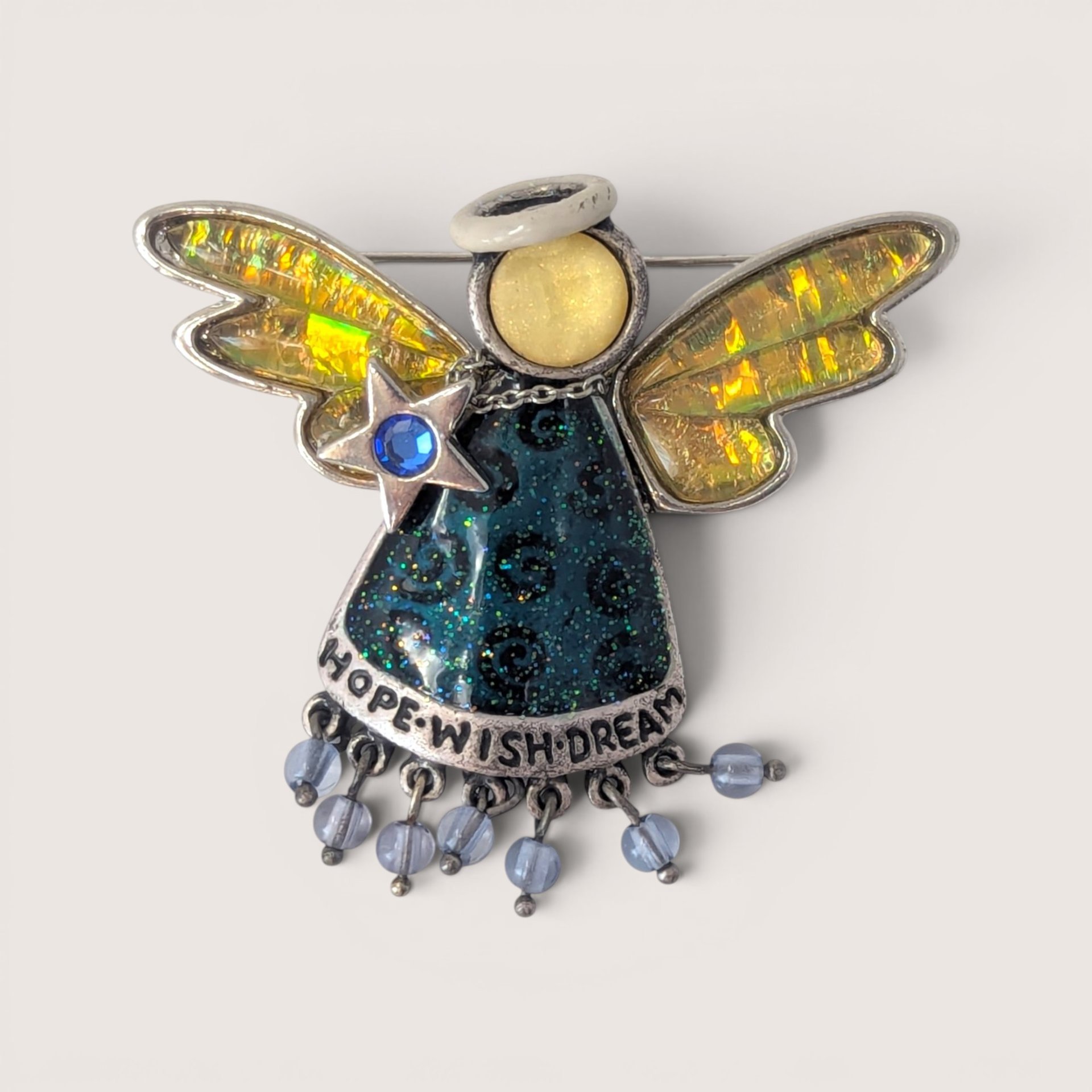 Vintage enamel and rhinestone angel brooch featuring iridescent wings, a glittery blue dress with "Hope Wish Dream" text, and dangling beads.