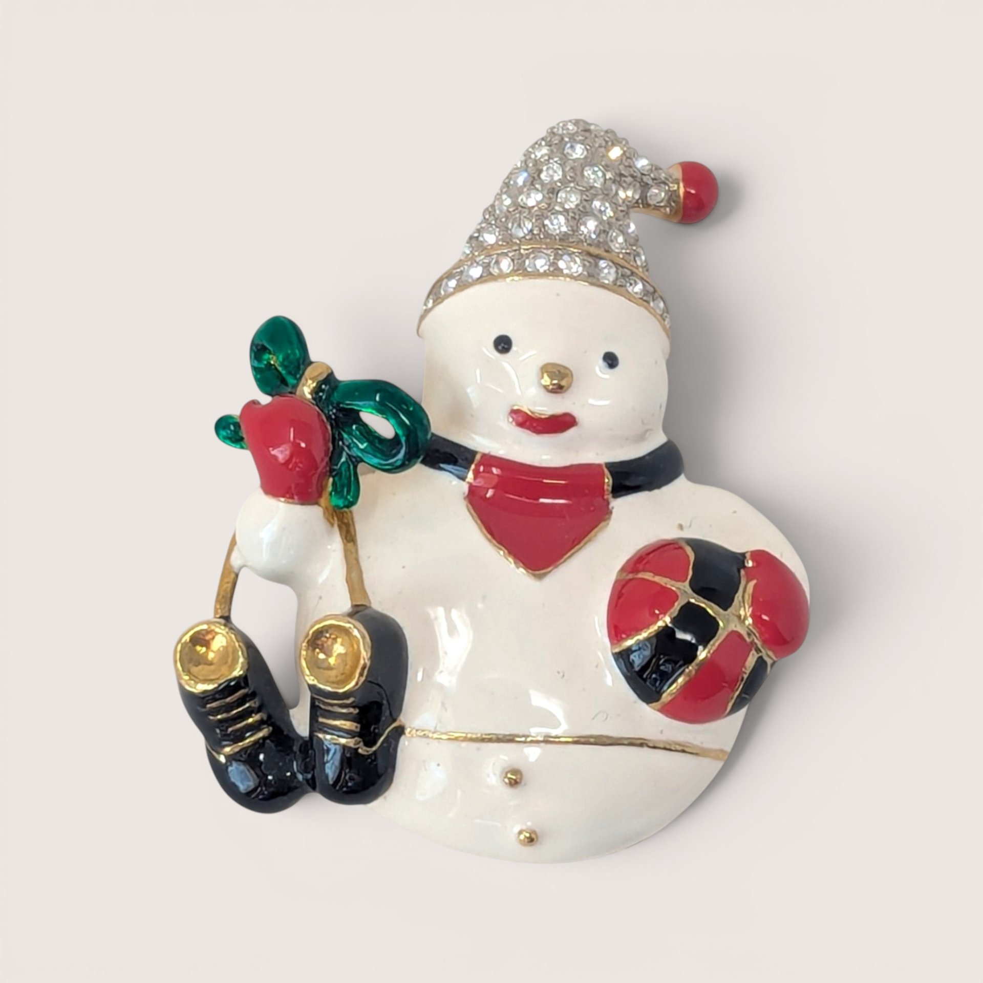 Vintage gold-tone enameled snowman brooch with rhinestone hat and red, green, and black details.