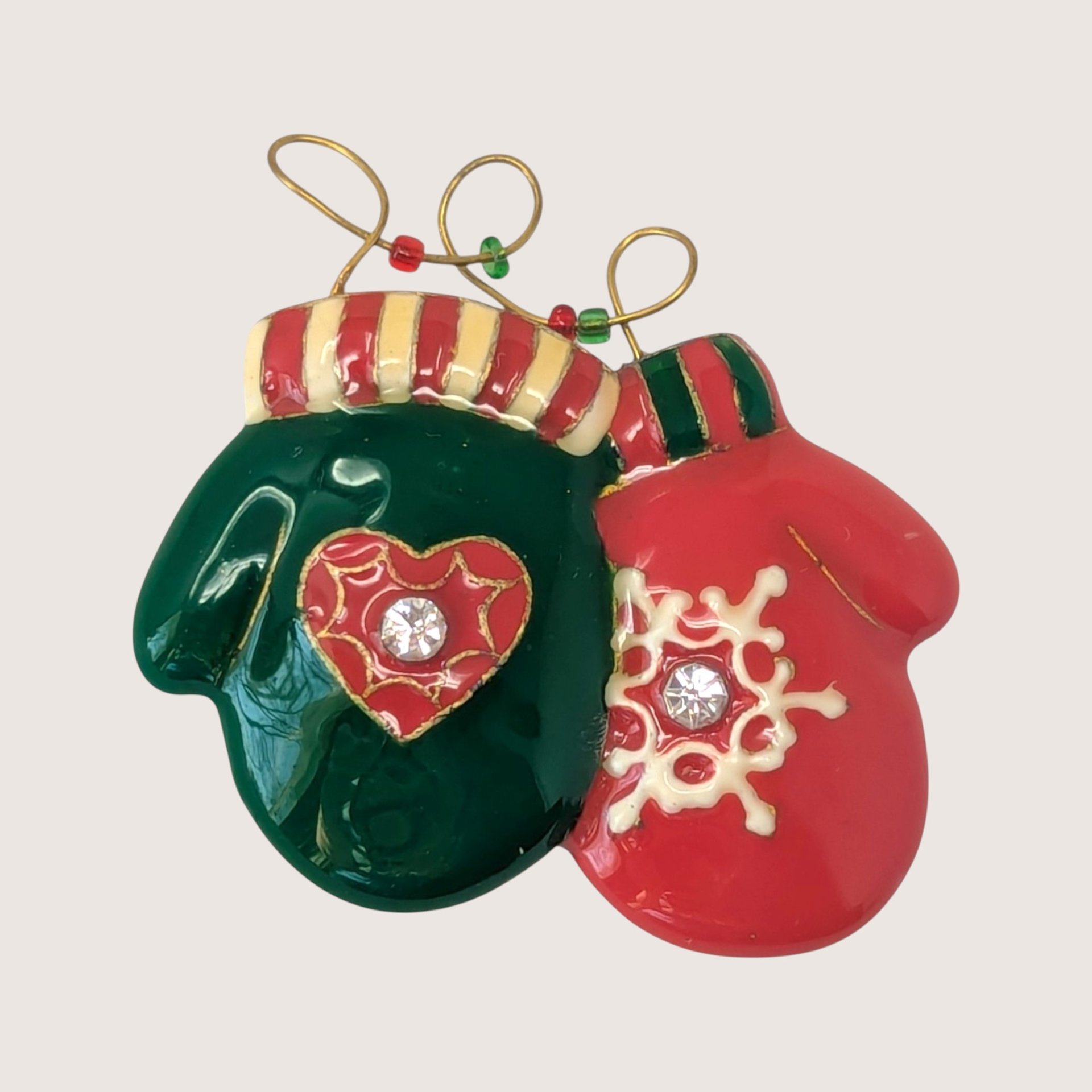Vintage gold-tone Christmas mittens brooch with red and green enamel, striped cuffs, and clear rhinestone hearts.