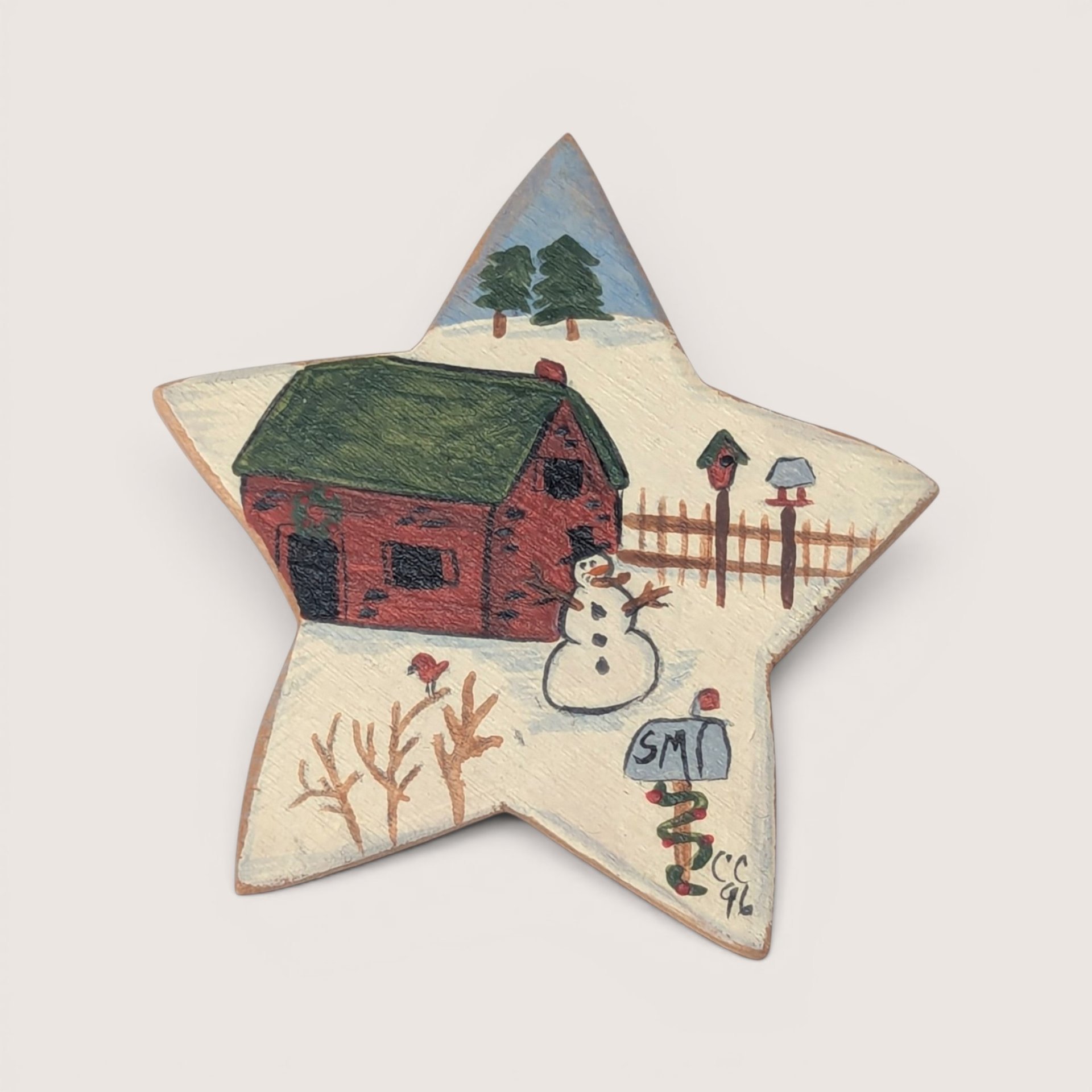 Hand-painted wooden star brooch featuring a winter cabin scene with a snowman, signed CC 96.