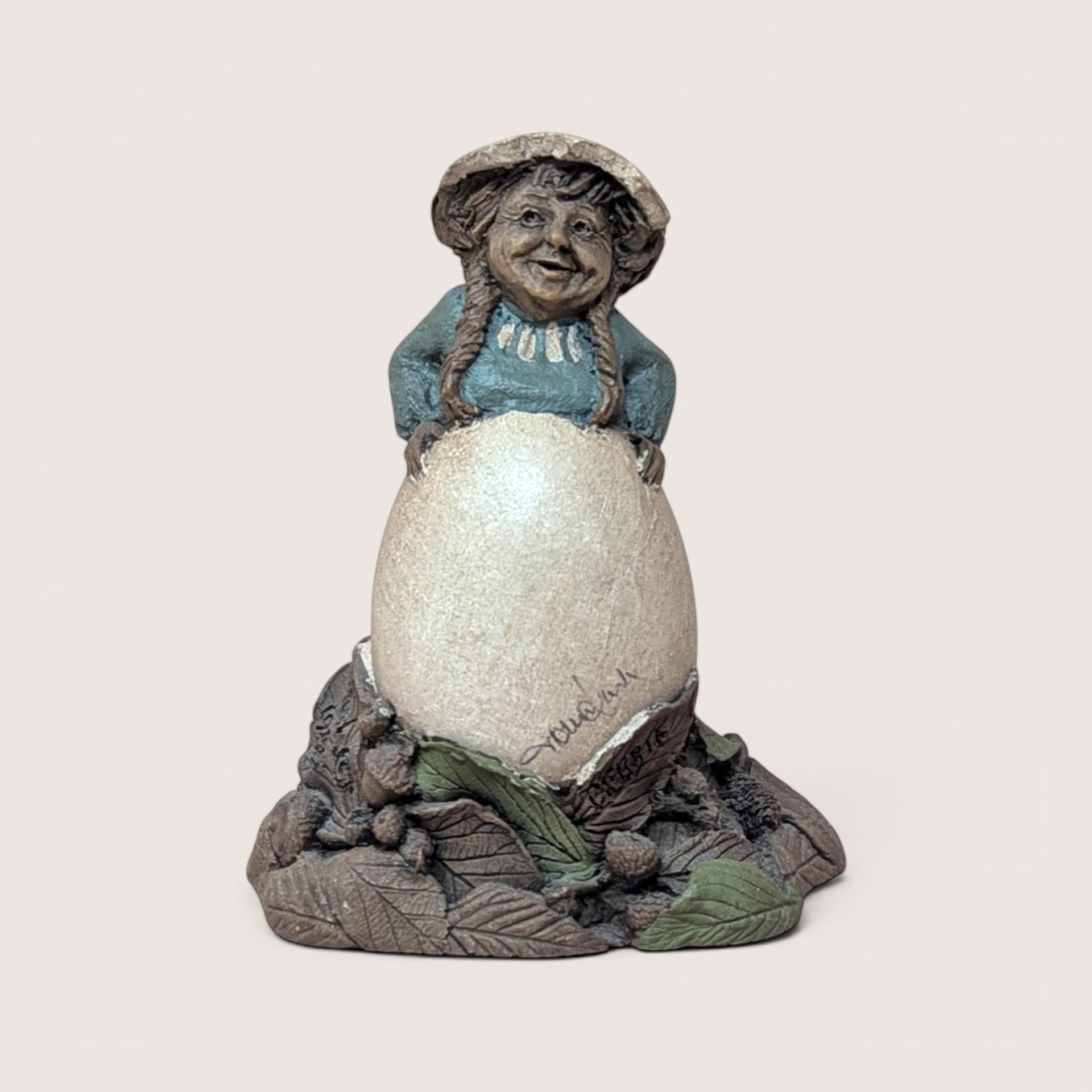 Vintage signed Tom Clark "Debbie" gnome figurine peeking over a large egg with natural leaf base.