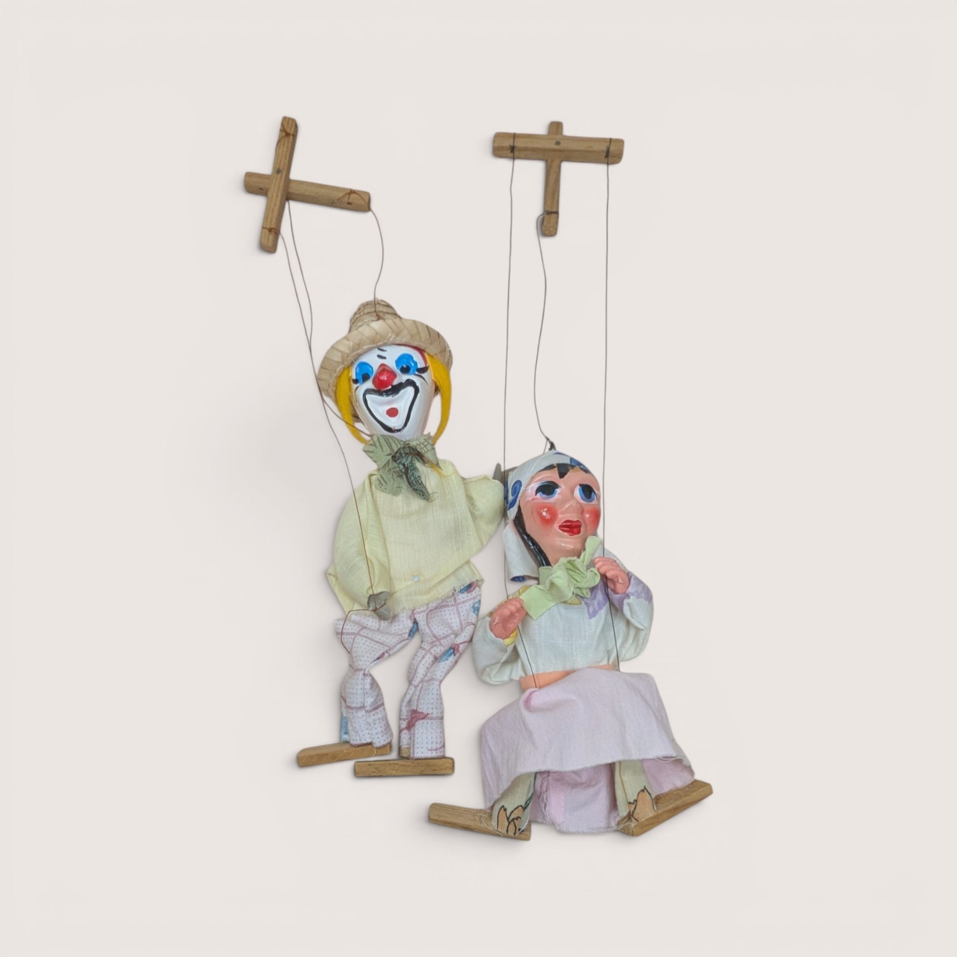 Pair of vintage string marionette puppets including a clown and companion figure with wooden control bars.