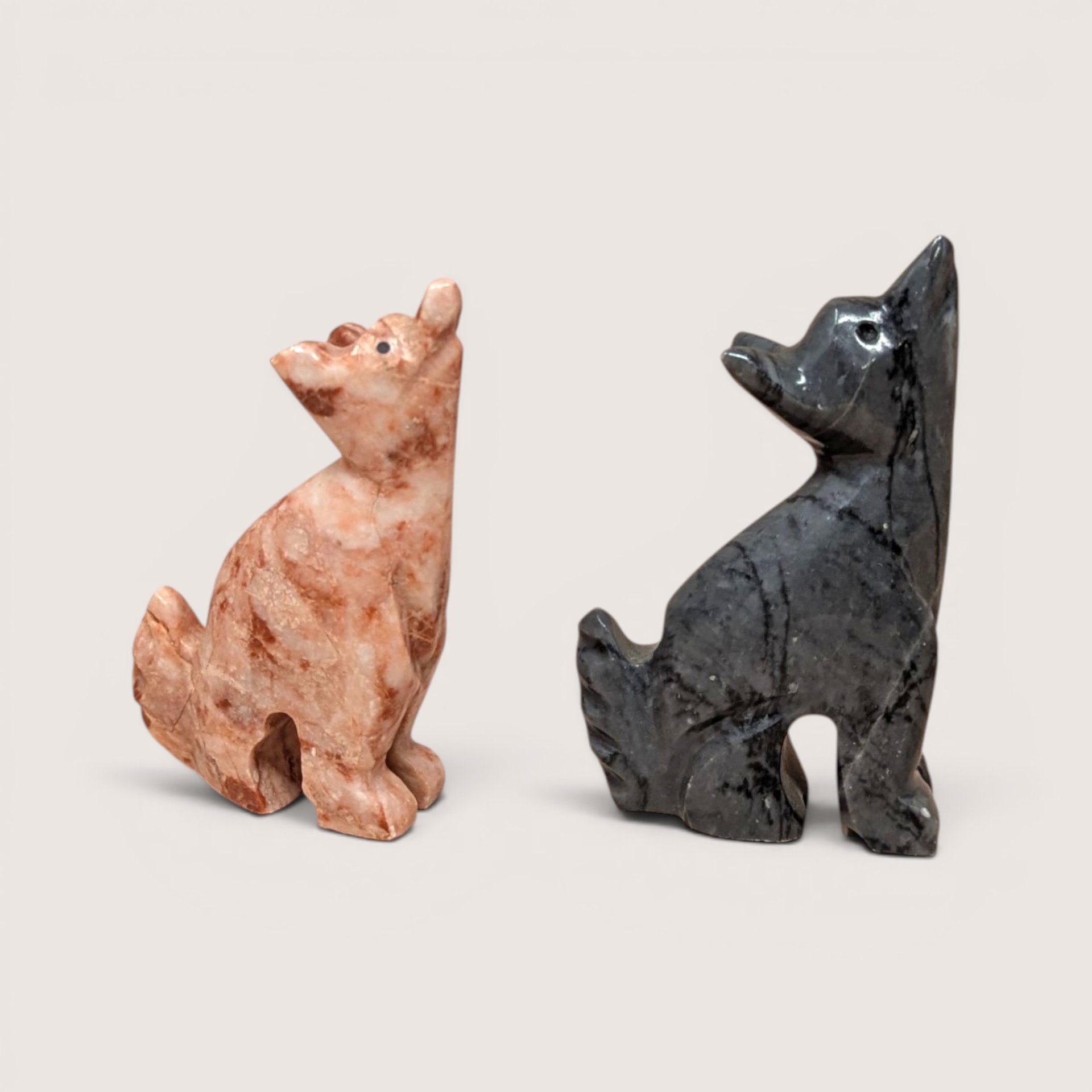 Vintage pair of hand-carved stone howling wolf figurines in pink and grey marble-style stone.