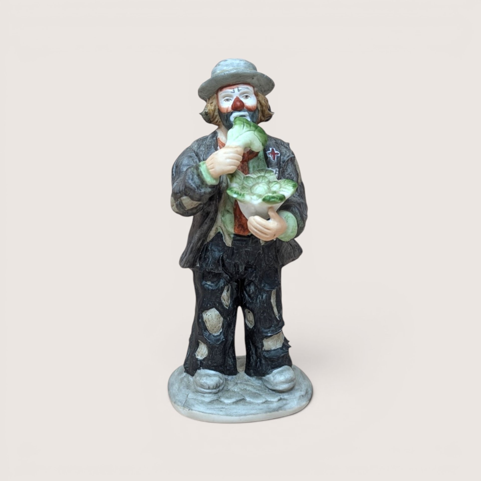 Vintage Flambro Emmett Kelly Jr ceramic figurine of Weary Willie eating lettuce.